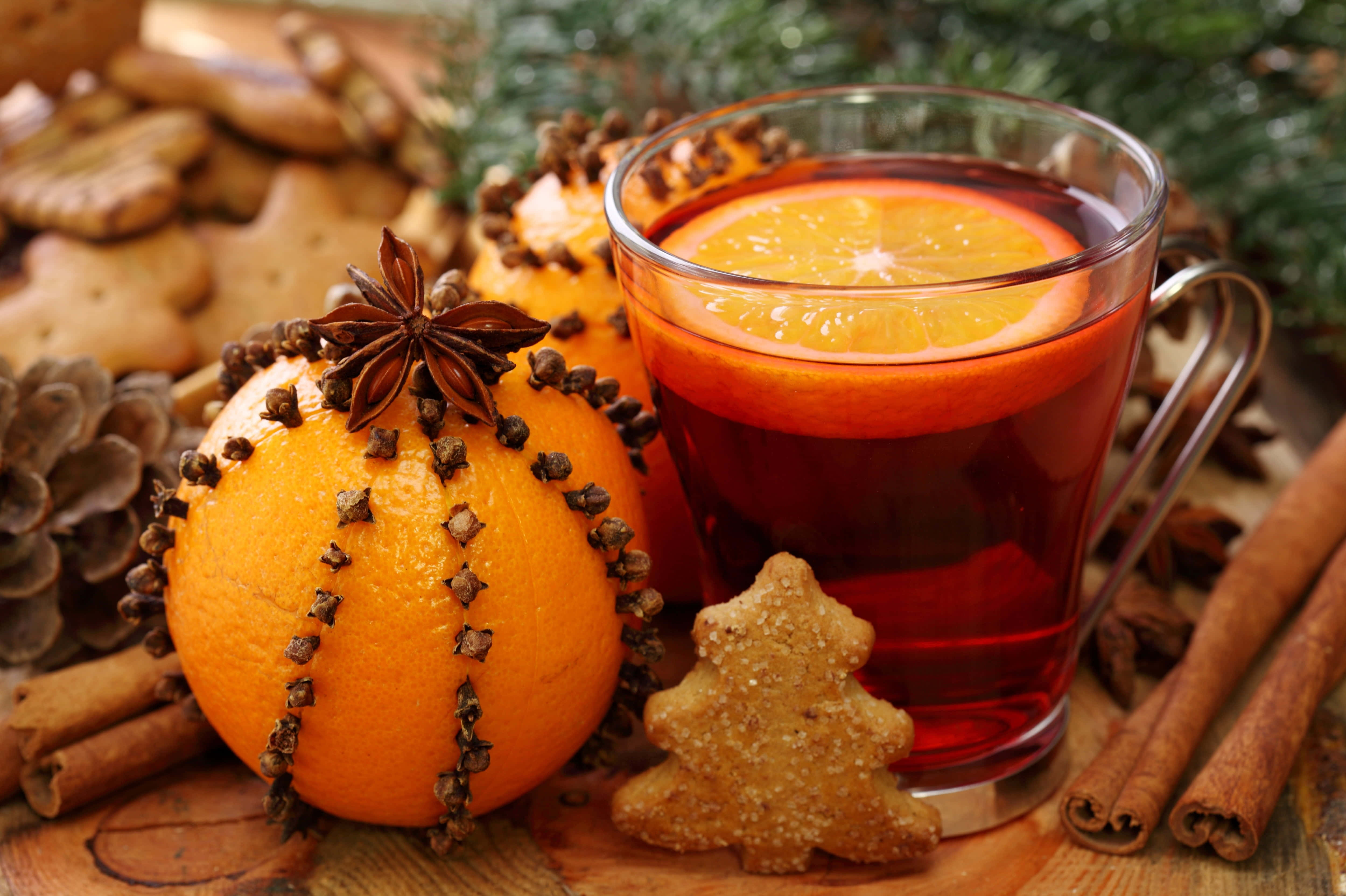 Mulled Wine 桌布 壁紙 — 一杯暖和的香料熱紅酒配柳橙片，旁邊放著插滿丁香柳橙和節日薑餅餅乾。