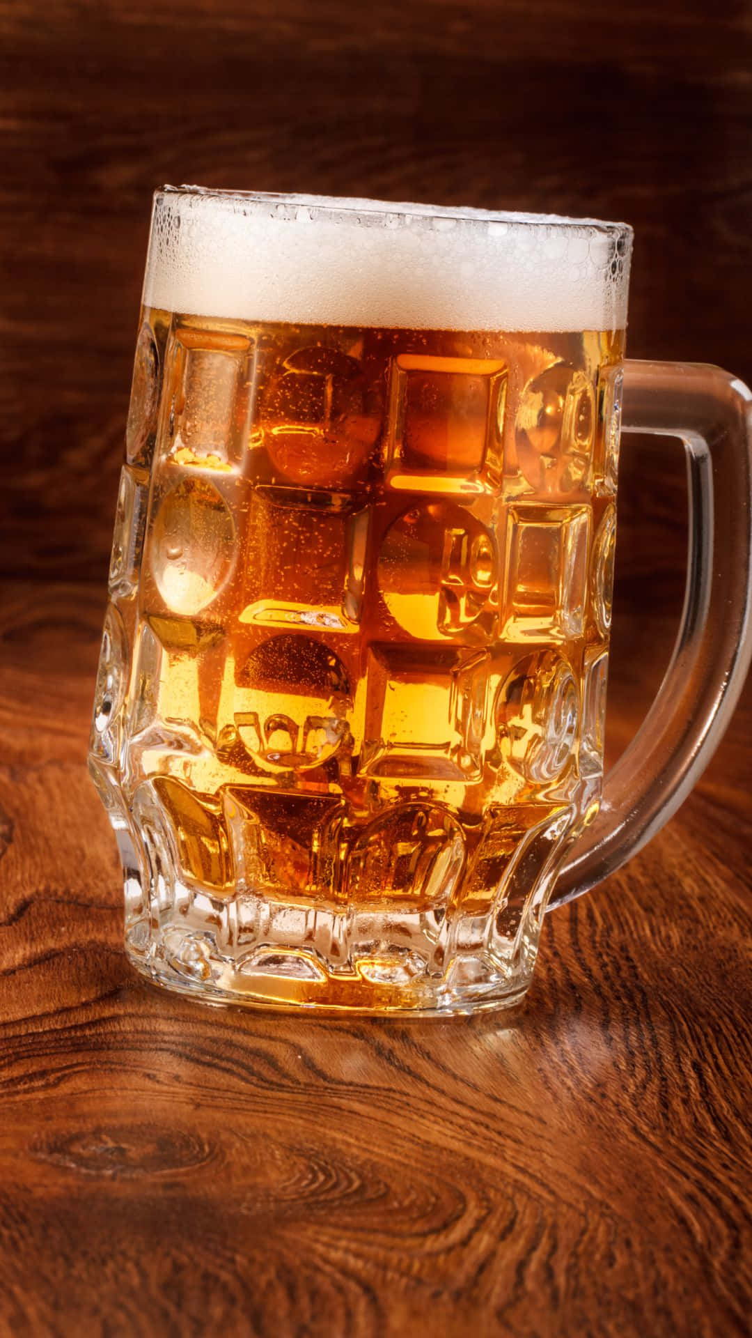 Beer 桌布 壁紙 — 一杯泡沫豐富的金色啤酒裝滿了一個有紋理的玻璃杯，放在一張濃郁的棕色木桌上。