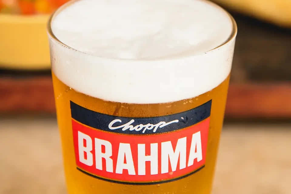 Drink 桌布 壁紙 — 一杯泡沫豐盈的 Brahma 啤酒杯特寫，帶有醒目的紅黑品牌標識，背景溫暖而模糊。