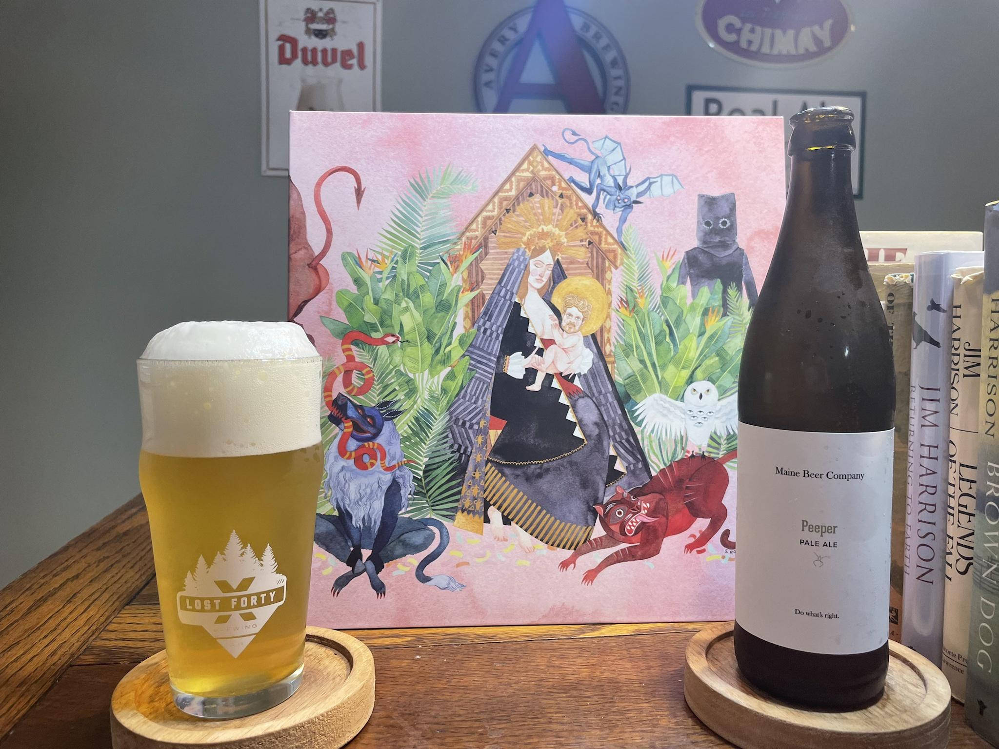 artwork 桌布 壁紙 — 一杯淡色艾爾啤酒和一瓶Peeper Pale Ale放在木杯墊上，旁邊是一張色彩繽紛的插圖海報，描繪神話生物和聖母瑪利亞般的人物。