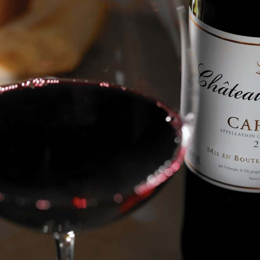 Black Wine 桌布 壁紙 — 一杯深紅酒的近距離特寫，旁邊是一瓶 Château 酒瓶，帶有柔和的散景燈光。