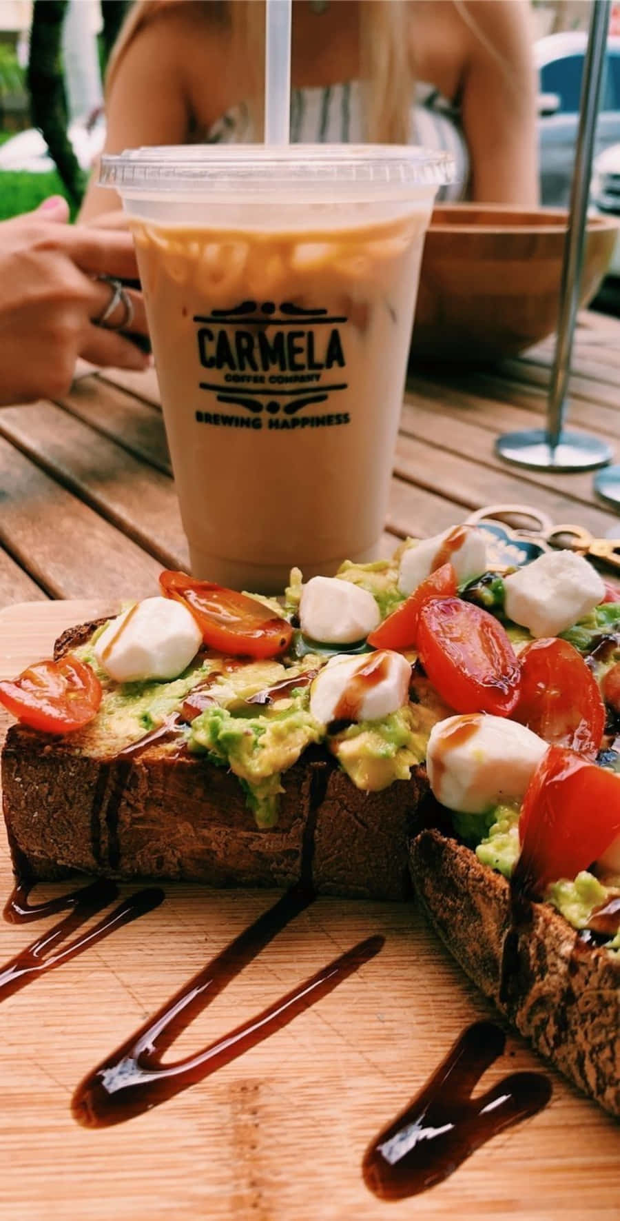 Aesthetic Food 桌布 壁紙 — 一杯清爽的冰咖啡和酪梨吐司，配上小番茄和莫札瑞拉起司，淋上巴薩米克醋，放在木桌上。
