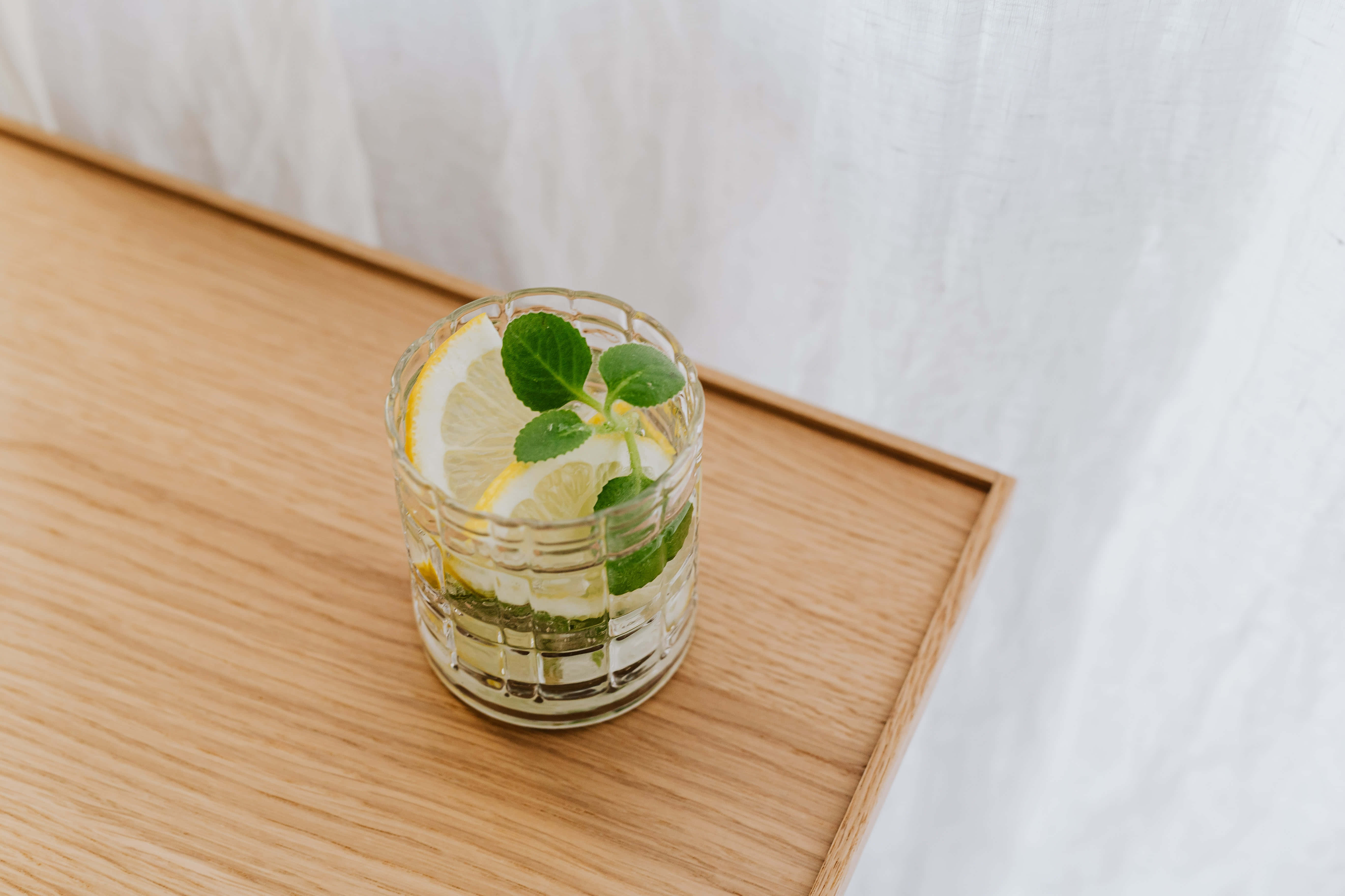 Summer Drinks 桌布 壁紙 — 一杯清爽的檸檬水搭配薄荷葉，放在淺色木托盤上，背景是柔軟的白色窗簾。