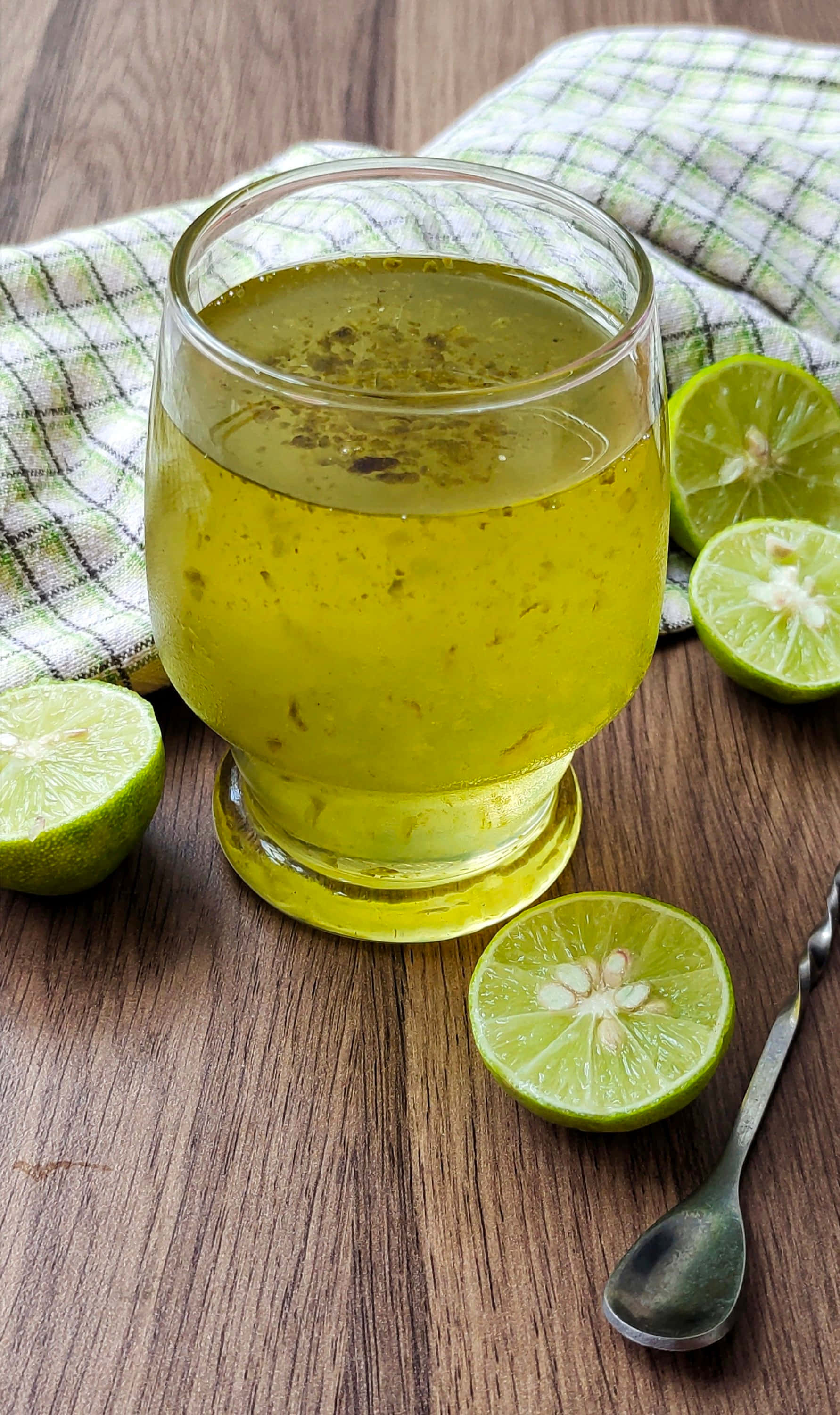 Fruit 桌布 壁紙 — 一杯清爽的萊姆飲品，配上新鮮萊姆片，放在木桌上，旁邊有格子餐巾和湯匙。