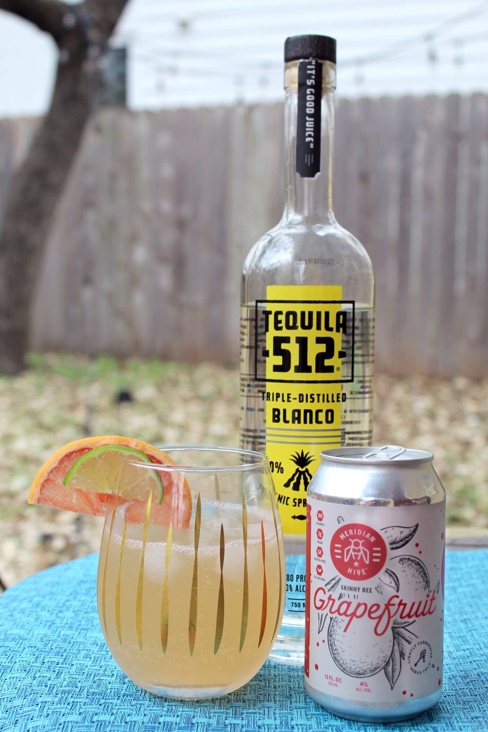 drinks 桌布 壁紙 — 一杯清爽的龍舌蘭雞尾酒搭配葡萄柚蘇打，旁邊放著一瓶Tequila 512，在藍色戶外桌上。