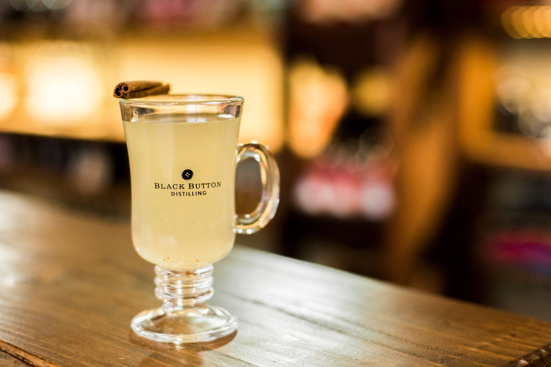 glass 桌布 壁紙 — 一杯溫暖的香料飲品，盛載於品牌玻璃杯，以肉桂棒點綴，放在木製吧檯上。