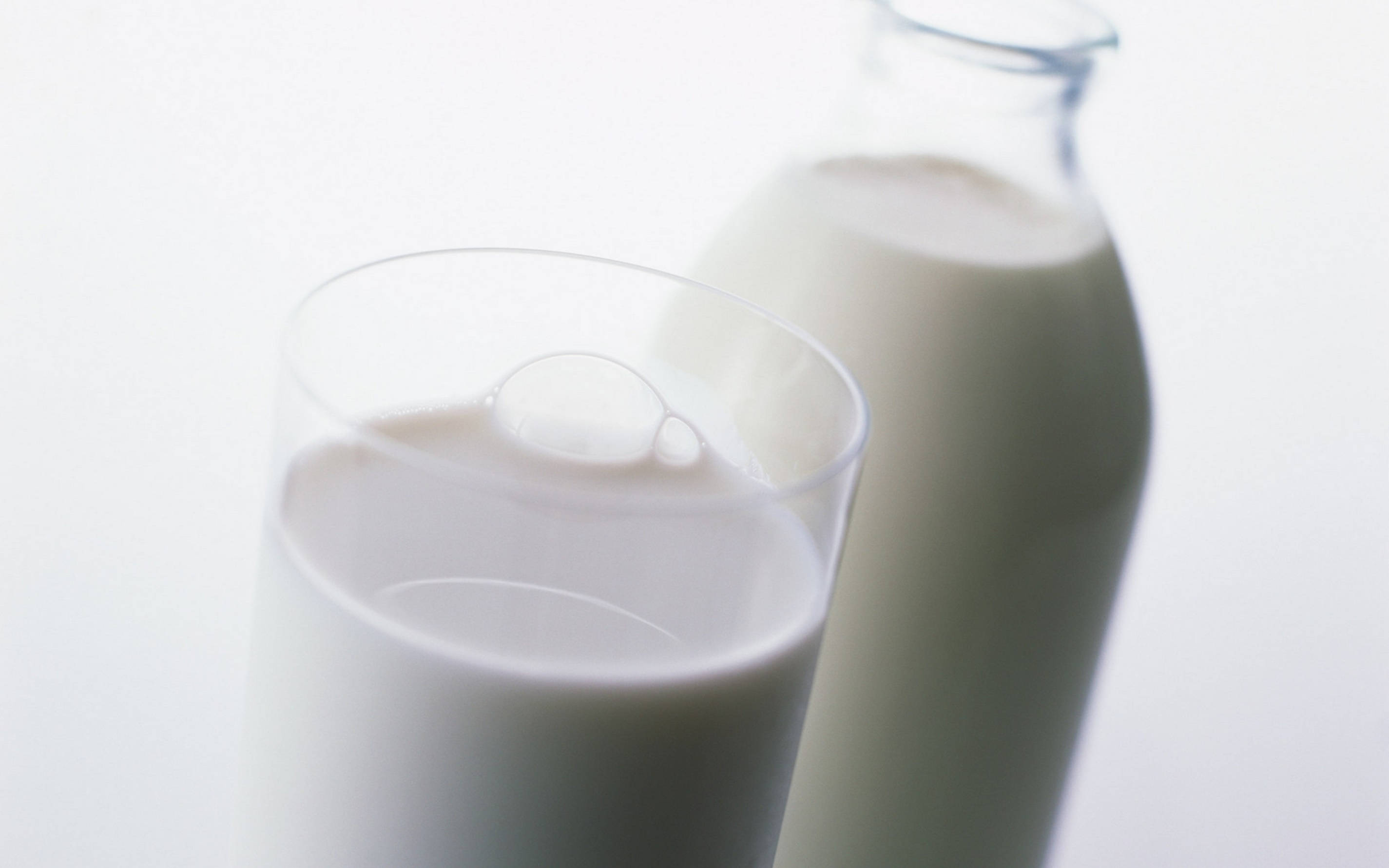 Milk 桌布 壁紙 — 一杯牛奶和牛奶瓶的特寫，光線柔和，景深較淺。