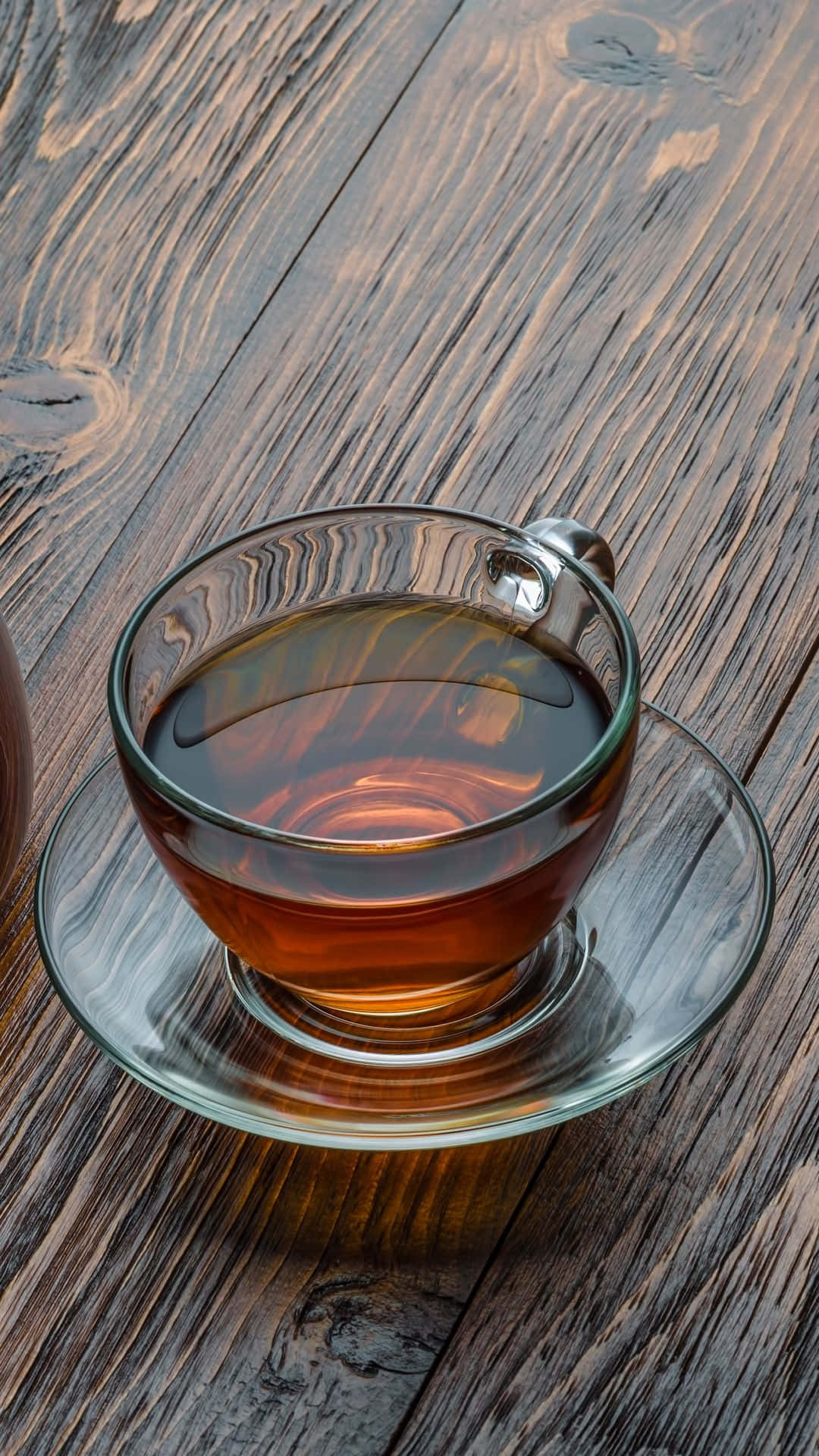 咖啡動圖 桌布 壁紙 — 一杯琥珀色茶的透明玻璃杯，放在相配的茶碟上，下面是一張風化的木桌。