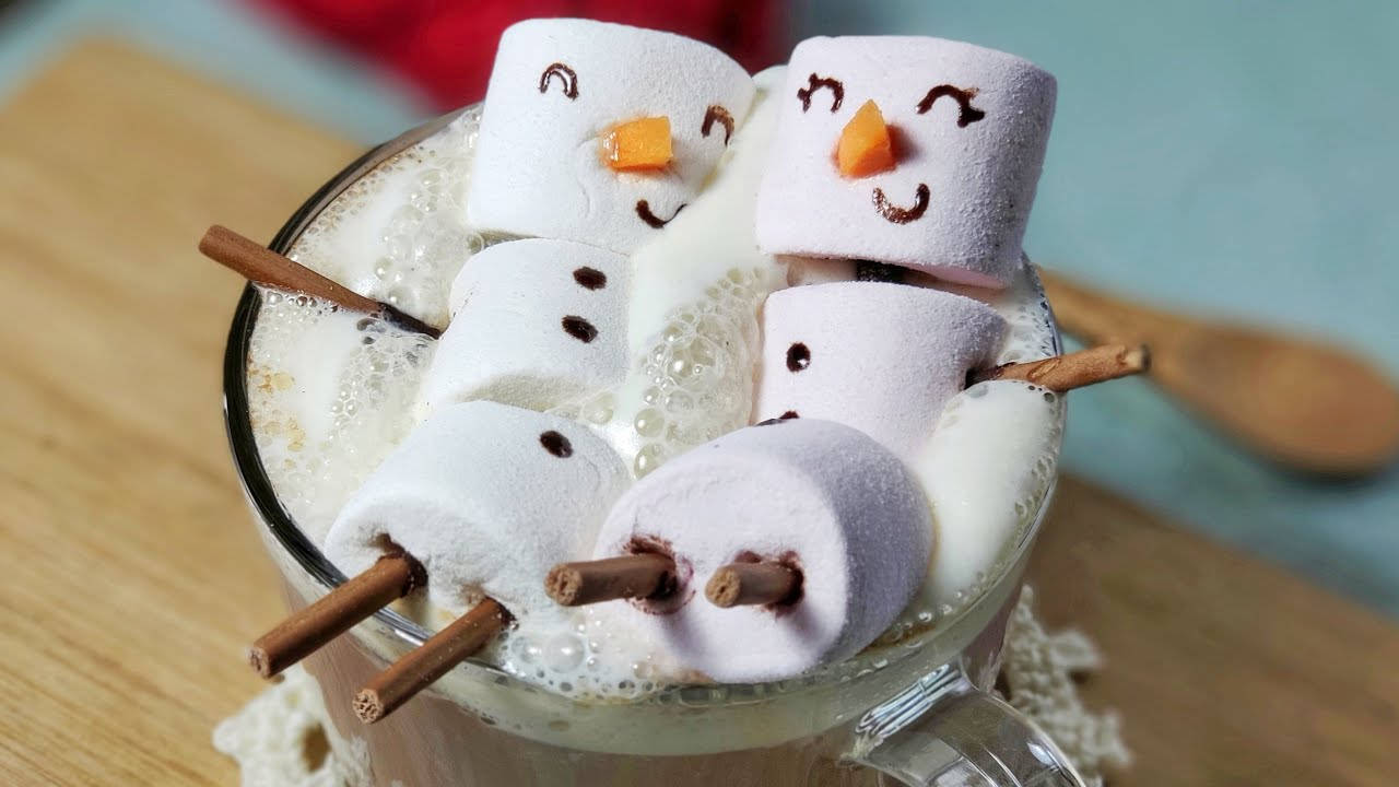 熱巧克力上面放著用肉桂棒製成的微笑棉花糖雪人。 — Squishmallows 壁紙