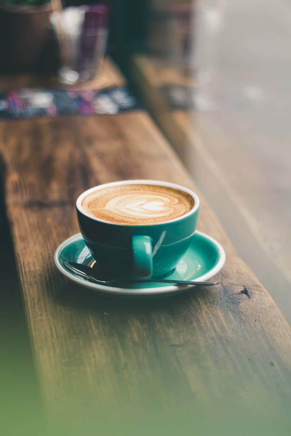 Coffee Cup 桌布 壁紙 — 一杯藍綠色的拉花咖啡放在鄉村風格的木桌上，伴隨著柔和自然光。