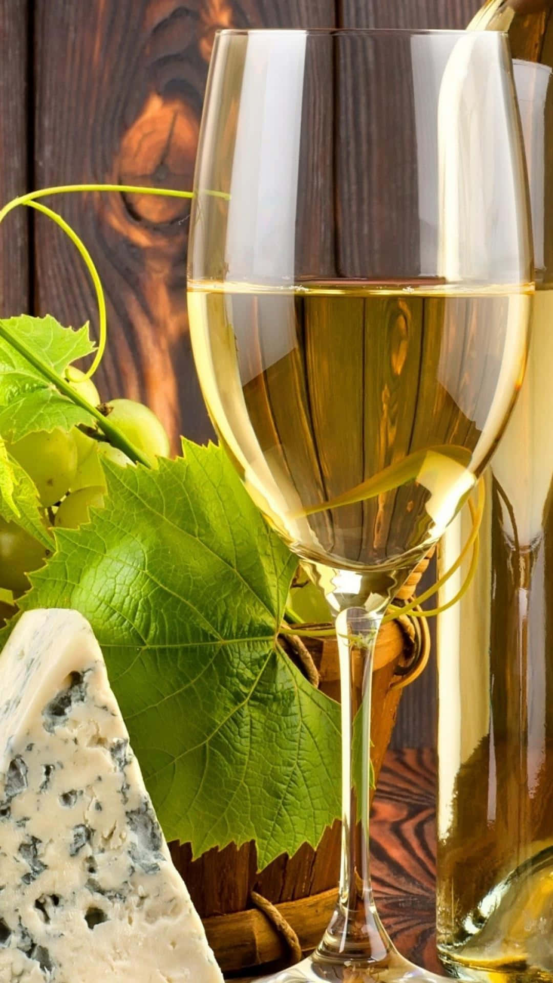 White Wine 桌布 壁紙 — 一杯金黃色的白葡萄酒放在鄉村風格的木桌上，旁邊有青提子和藍紋起司。