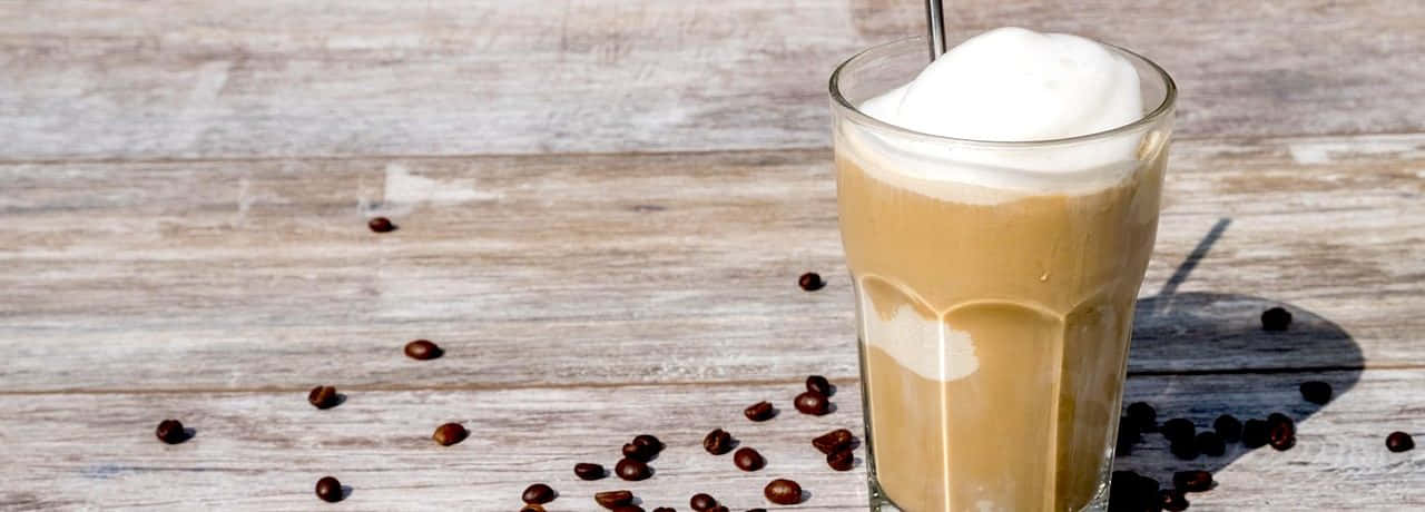 Milk And Coffee 桌布 壁紙 — 一杯高身忌廉冰咖啡，上面有鮮奶油，咖啡豆散落在經風化的木質表面上。