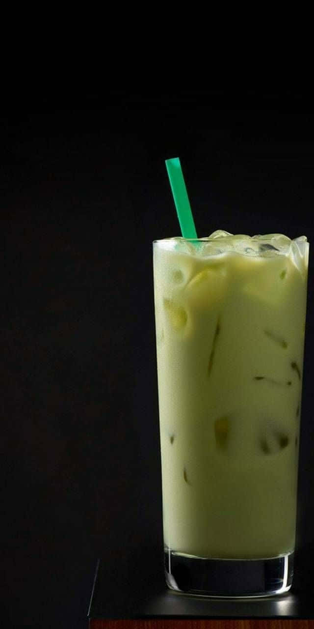 Matcha 桌布 壁紙 — 一杯高身的奶油冰抹茶拿鐵，有冰塊和綠色吸管，襯黑色背景。