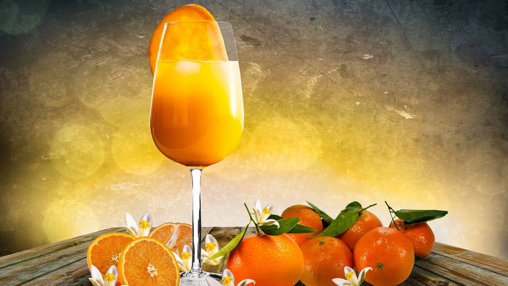 Orange Fruit 桌布 壁紙 — 一杯高身鮮豔橙汁，加冰和一片柑橘，旁邊放著新鮮橙子和花朵，在質樸的木桌上。