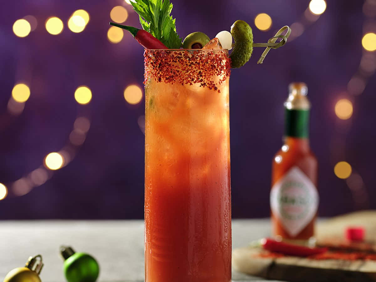 Spicy 桌布 壁紙 — 一杯鮮紅的Bloody Mary雞尾酒，飾以辣椒醃菜和芹菜，襯以紫色背景和溫暖的散景燈光。