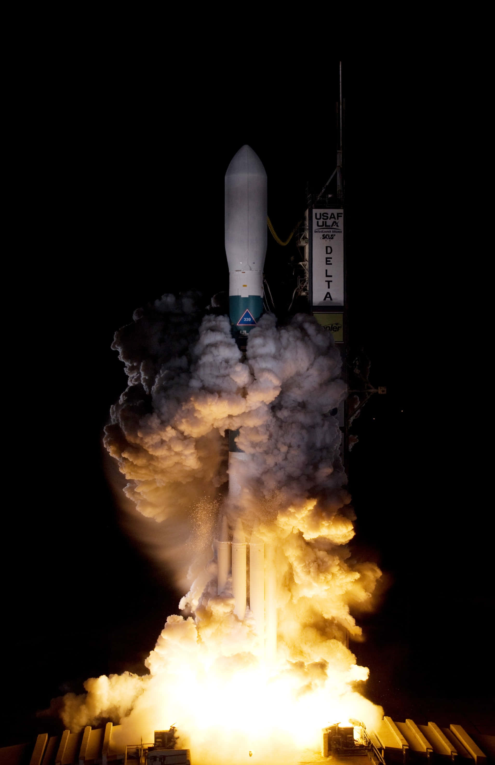 Space Mission 桌布 壁紙 — 一枚三角洲火箭在漆黑的夜空中點火，噴射出熾熱的推力和滾滾濃煙。