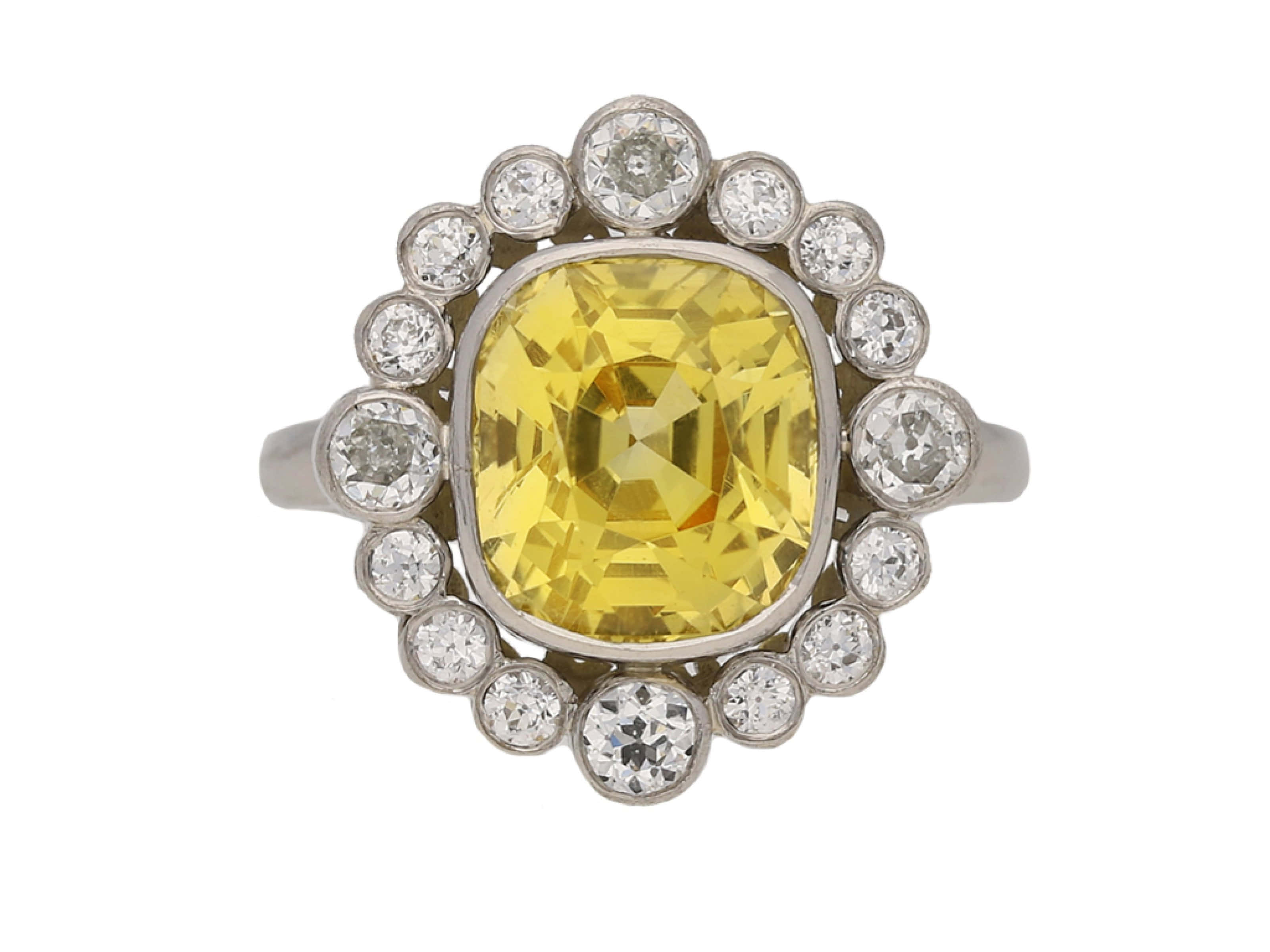 Yellow Sapphire 桌布 壁紙 — 一枚令人驚嘆的復古戒指，鑲有一顆大型枕形切割黃色寶石，周圍環繞著閃爍鑽石光環。