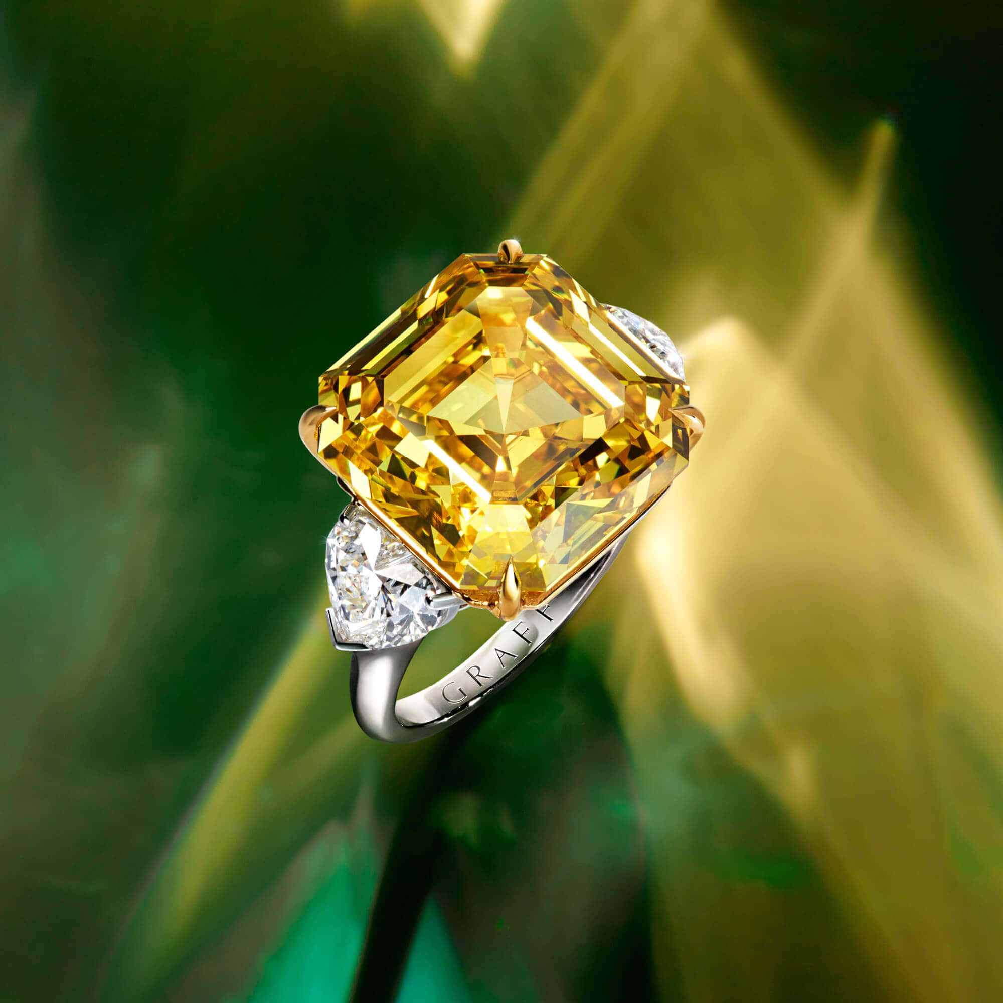 Yellow Diamond 桌布 壁紙 — 一枚令人驚嘆的黃色枕形切割鑽石戒指，鑲有白色鑽石，背景為充滿活力的綠色和金色抽象圖案。
