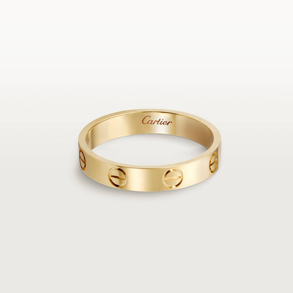 Ring 桌布 壁紙 — 一枚光滑的黃金卡地亞 love 戒指，帶有標誌性的螺絲圖案，在極簡白色背景上閃耀。