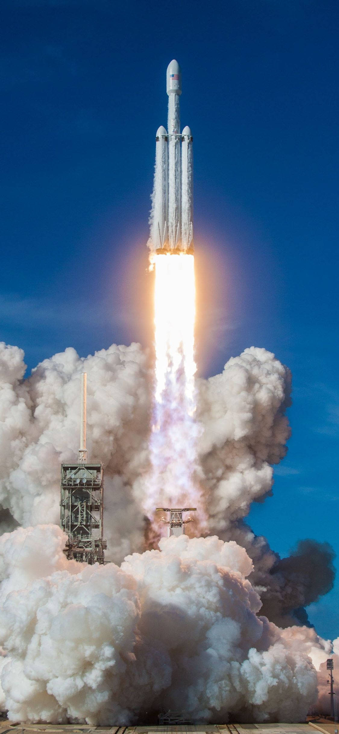 SpaceX 桌布 壁紙 — 一枚強大的火箭升上晴朗的藍天，發射時留下熾熱的軌跡和滾滾白煙。