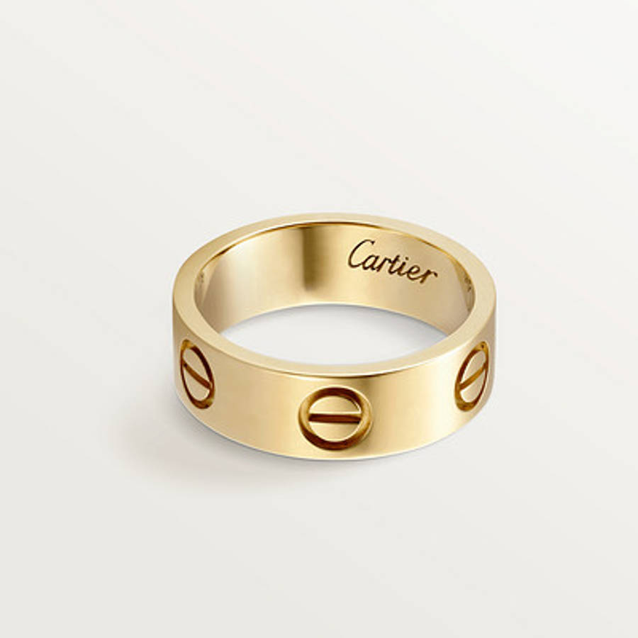 Ring 桌布 壁紙 — 一枚拋光金色Cartier love戒指，帶有三個螺絲圖案和刻有品牌名稱，置於潔白背景上。