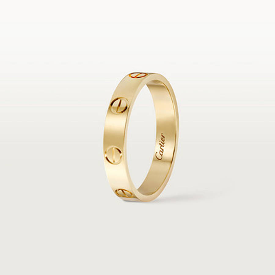 Ring 桌布 壁紙 — 一枚時尚的黃金卡地亞Love戒指，帶有標誌性的螺絲圖案和刻字品牌名稱，背景為柔和漸變色。