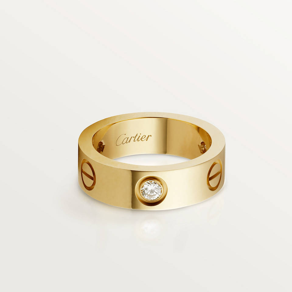 Ring 桌布 壁紙 — 一枚時尚的黃金卡地亞戒指，中央鑲有鑽石和標誌性螺絲，在簡約的白色背景下閃閃發光。