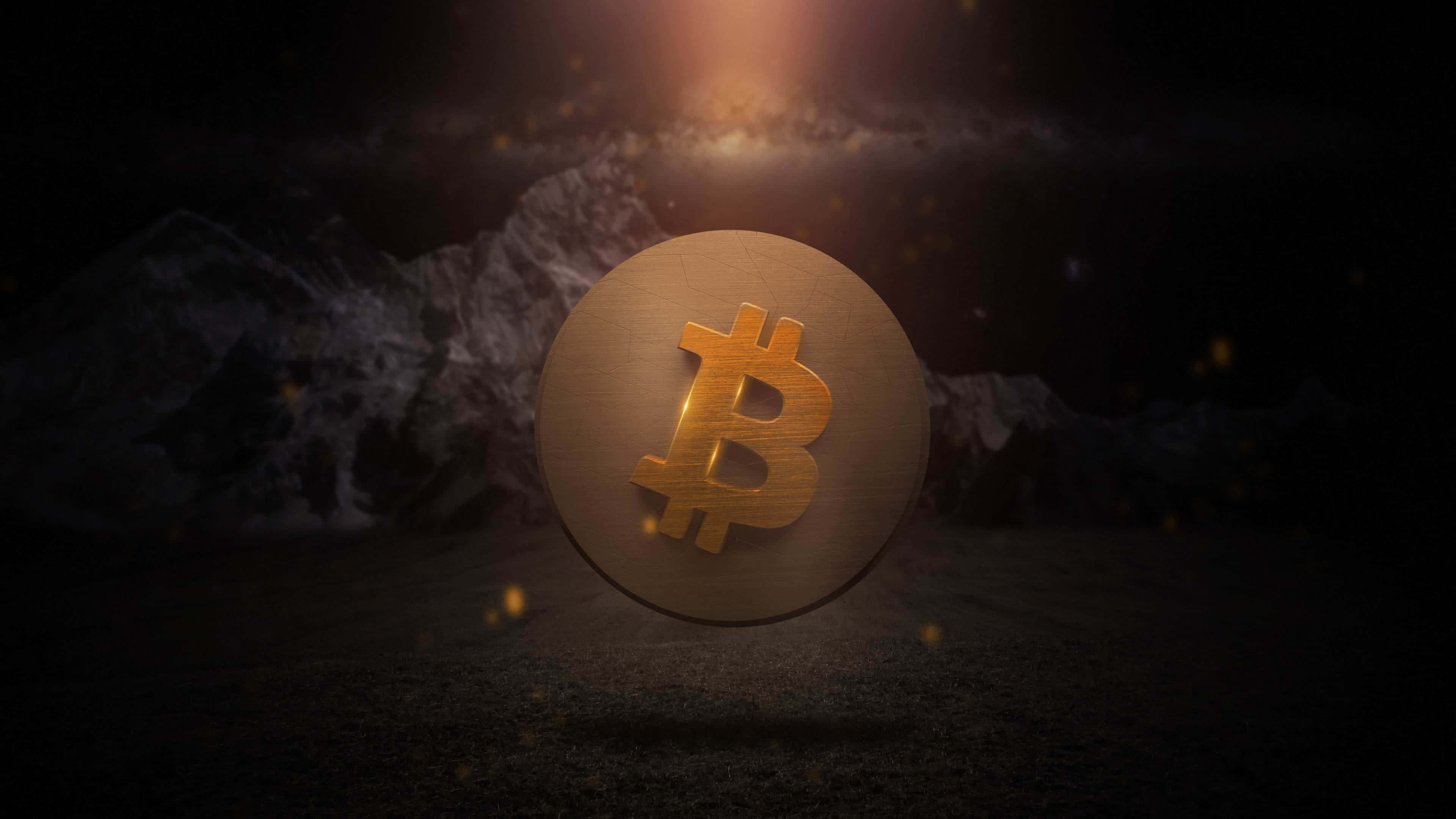 4K Bitcoin 桌布 壁紙 — 一枚發光的金色比特幣硬幣懸浮在黑暗的山地地形上，下方有耀眼的光束。