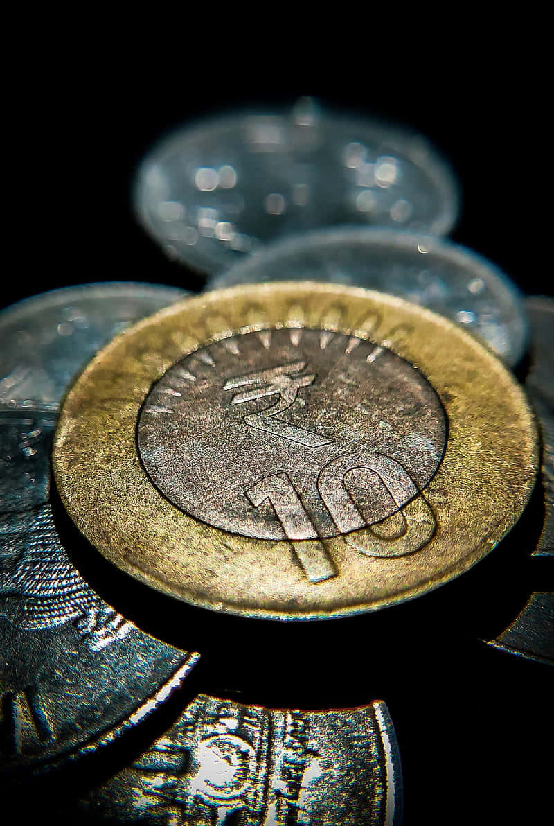 金錢 桌布 壁紙 — 一枚磨損的印度10盧比硬幣特寫，背後有模糊的硬幣，黑色背景。