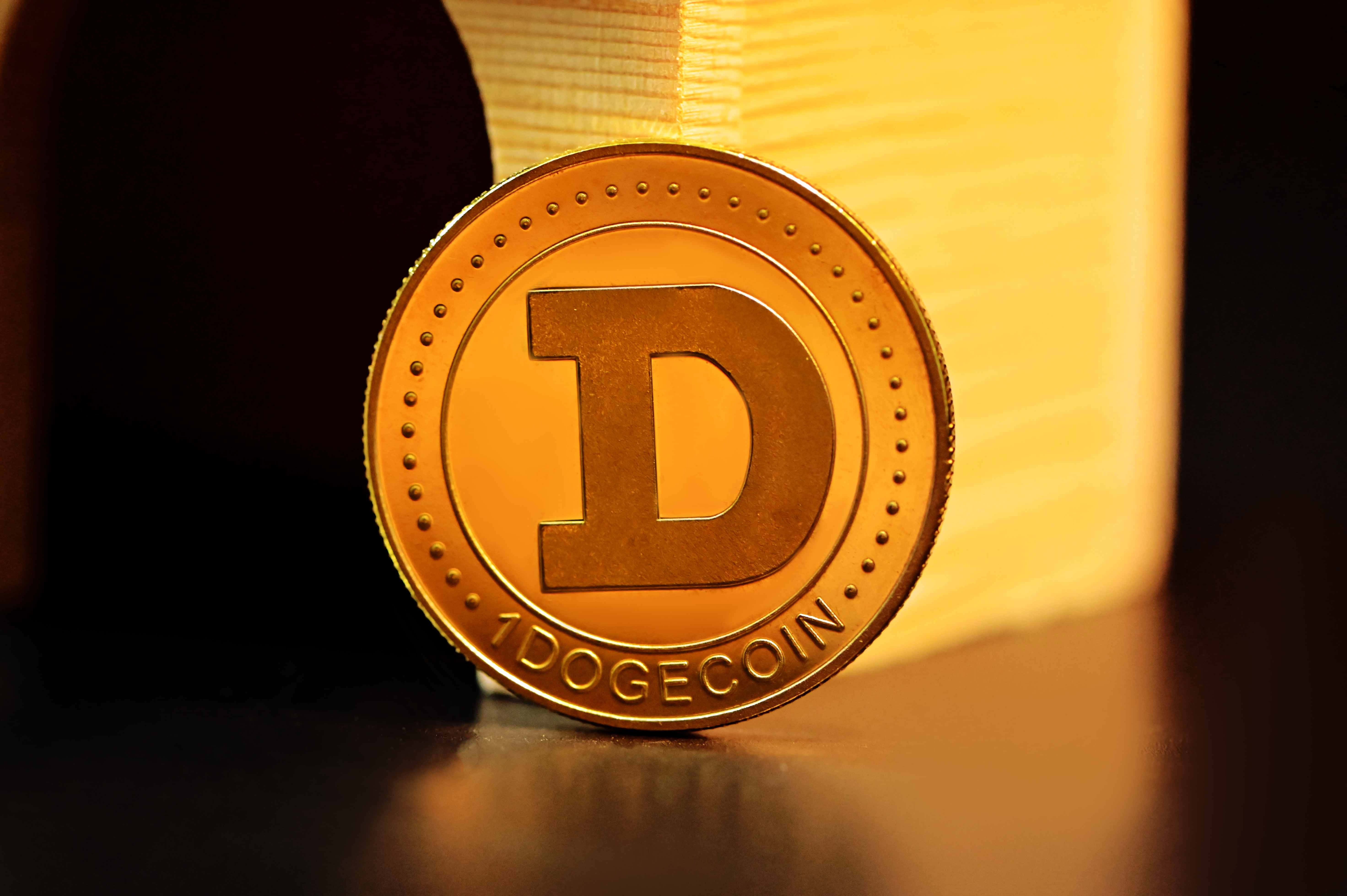 Dogecoin 桌布 壁紙 — 一枚金色 Dogecoin 代幣放置在反射表面上，沐浴在溫暖的背光中，帶有柔和陰影。