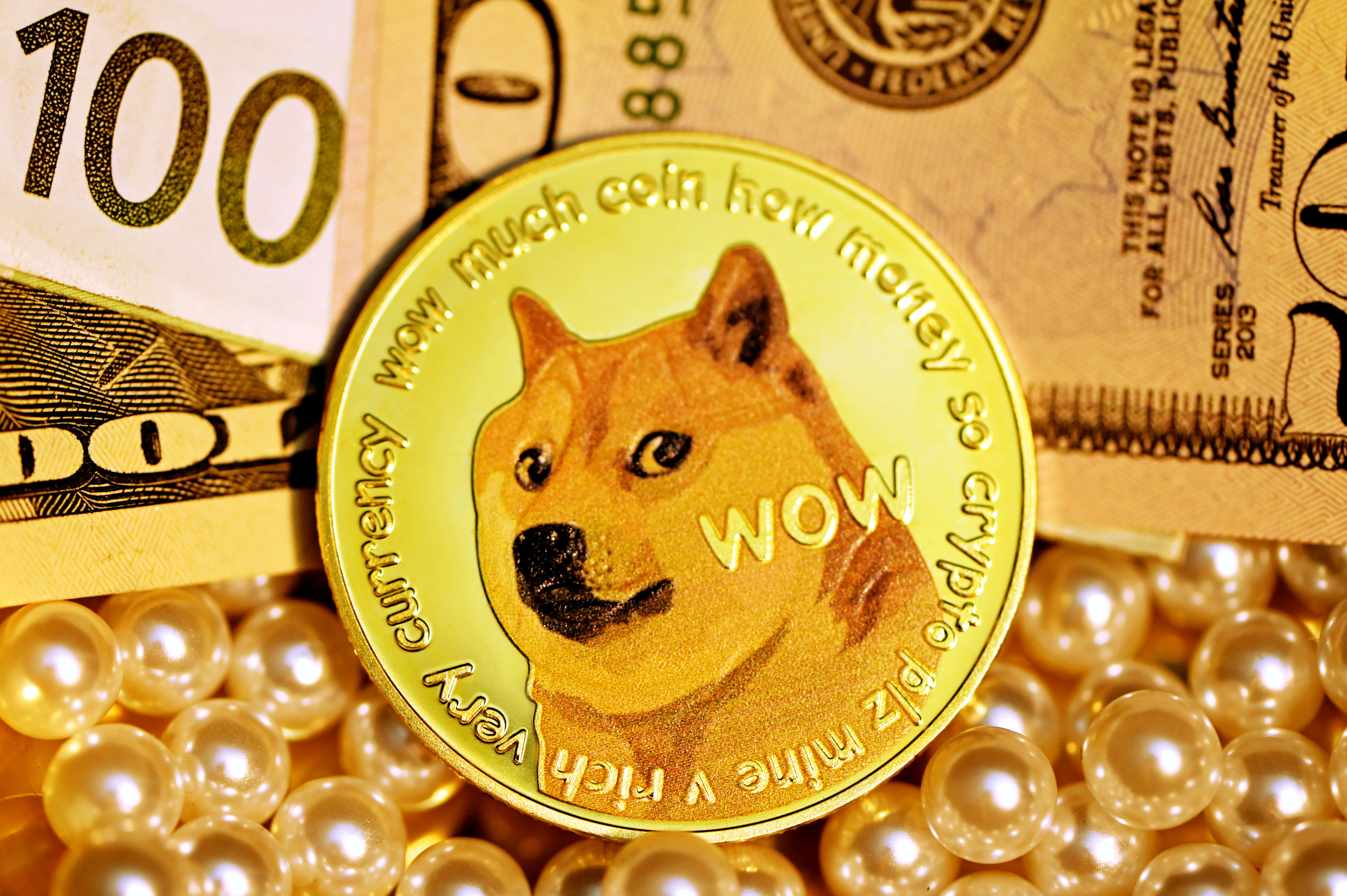 Dogecoin 桌布 壁紙 — 一枚金色Dogecoin放在美國百元鈔票和珍珠上，象徵加密貨幣財富和數位貨幣。