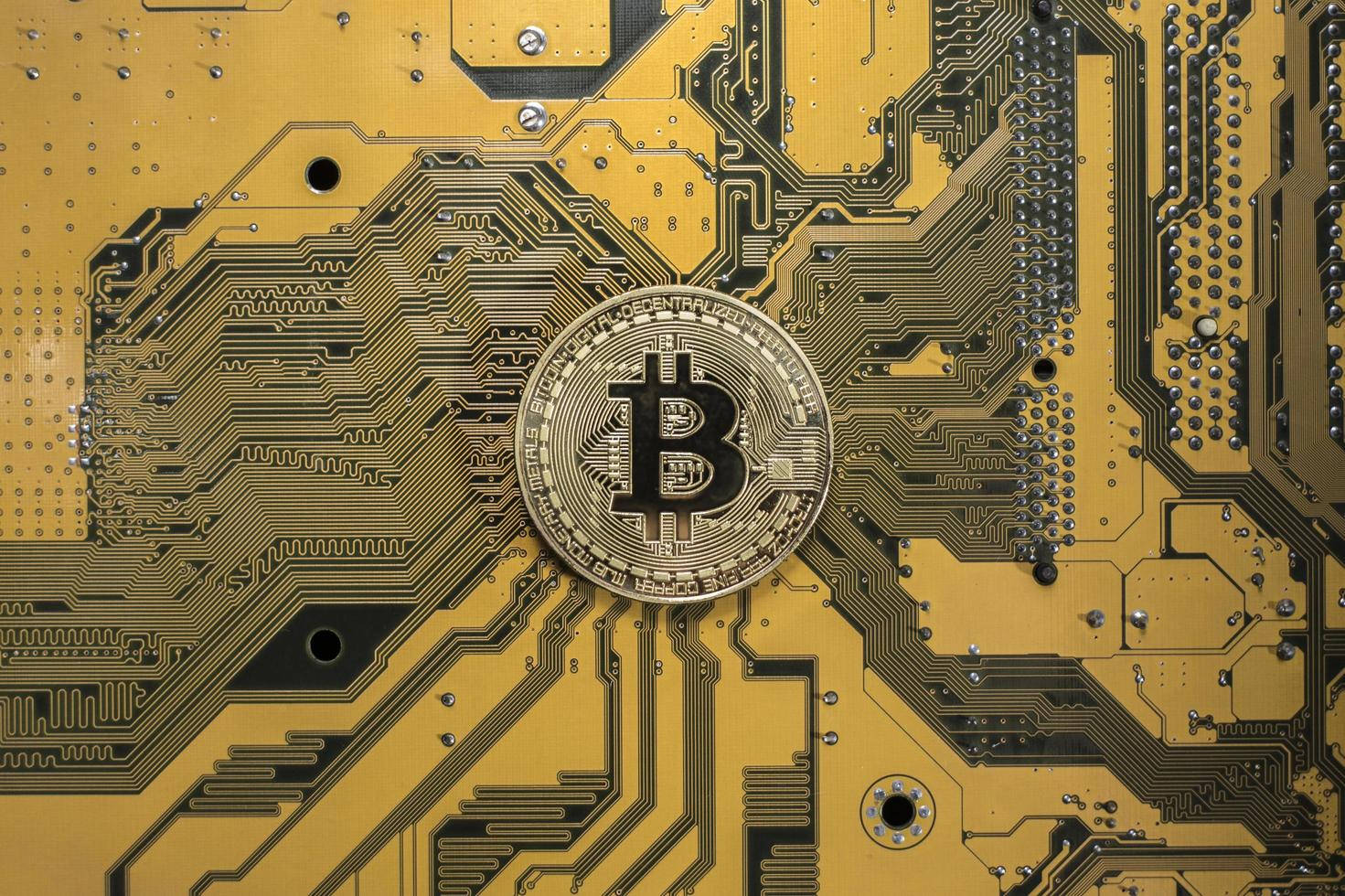 Cryptocurrency 桌布 壁紙 — 一枚金色比特幣硬幣放置在一個細節豐富的黃色電路板中央，上面有錯綜複雜的黑色線路。