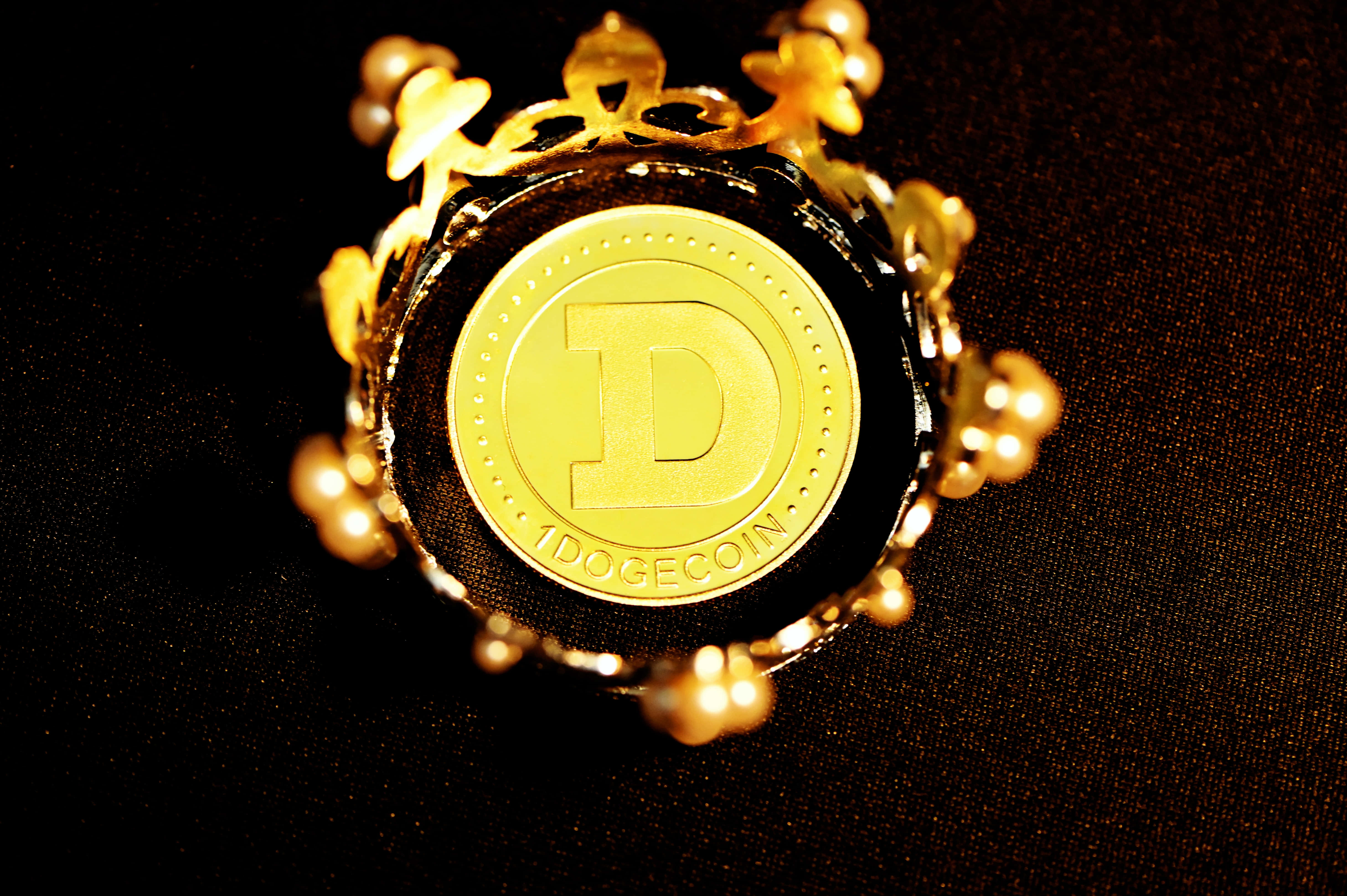 Dogecoin 桌布 壁紙 — 一枚金色狗狗幣被華麗的鏤空花絲和珍珠環繞，在溫暖燈光下放置於深色紋理表面上。
