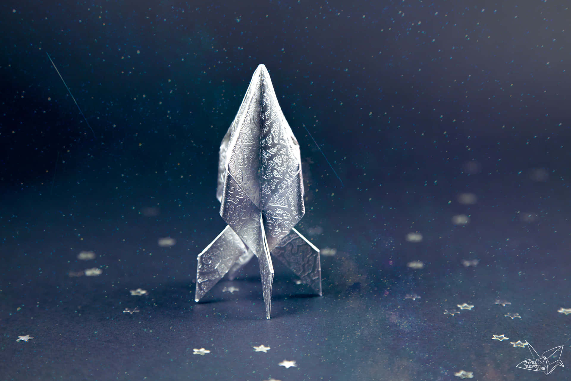 Spaceship 桌布 壁紙 — 一枚銀色摺紙火箭在深藍色夜空下，佇立於星光閃爍的宇宙表面。