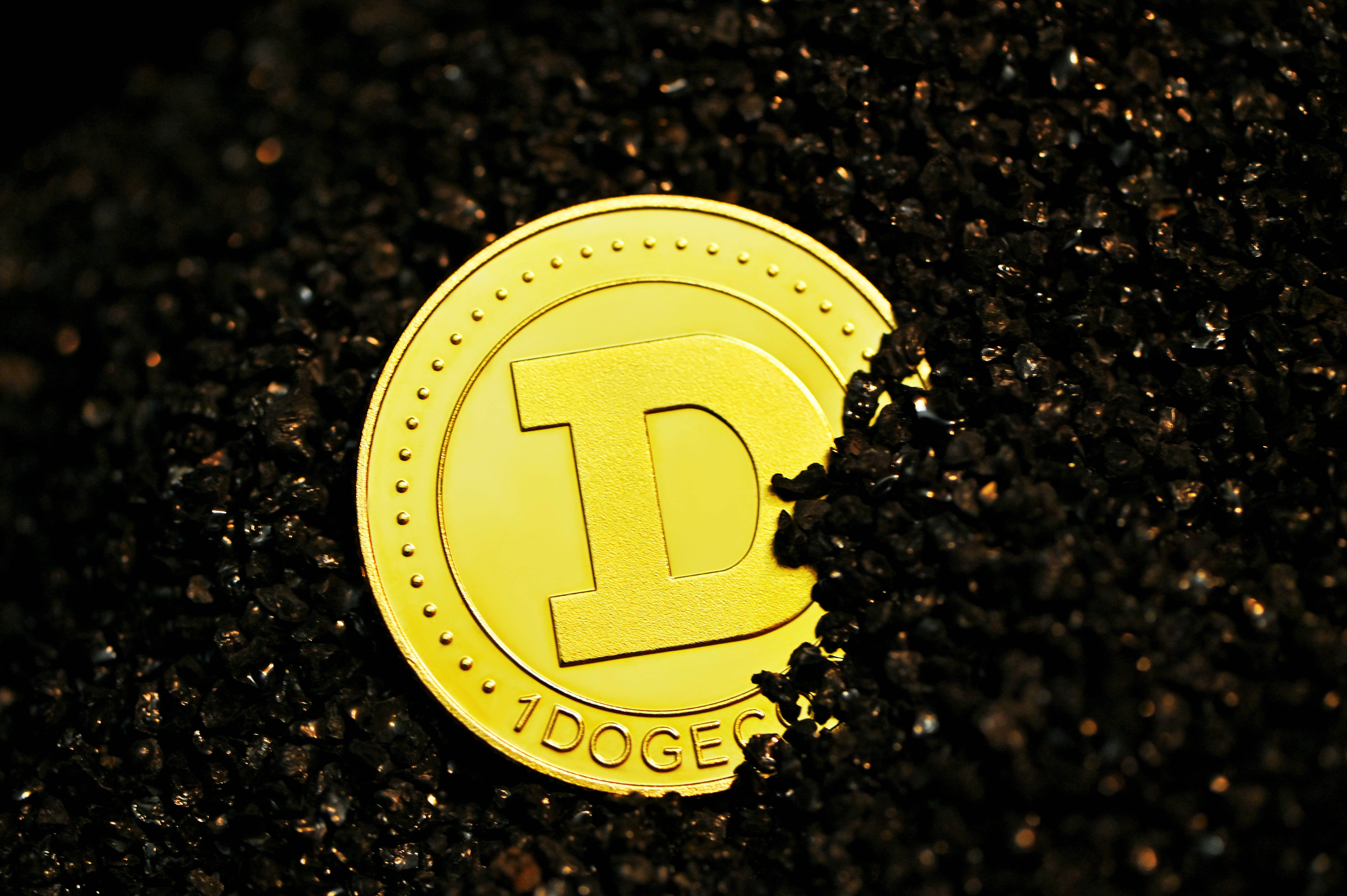 Dogecoin 桌布 壁紙 — 一枚閃閃發光的金色狗狗幣部分埋在深色有紋理的土壤中，在聚焦照明下。