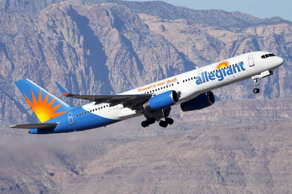 transportation 桌布 壁紙 — 一架 Allegiant Airlines 噴射機放下起落架，在晴朗藍天下飛過崎嶇的沙漠山脈。
