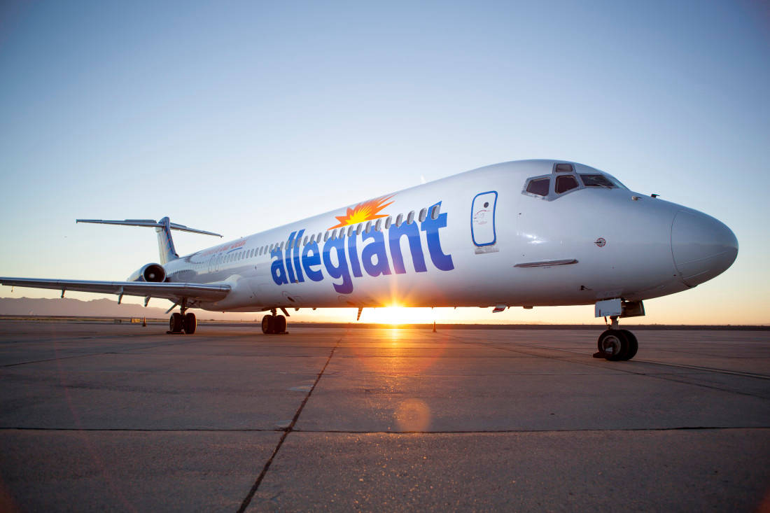  壁紙 — 一架 Allegiant Airlines 噴射機停在跑道上，太陽在它背後升起，在停機坪上投下金色光芒。