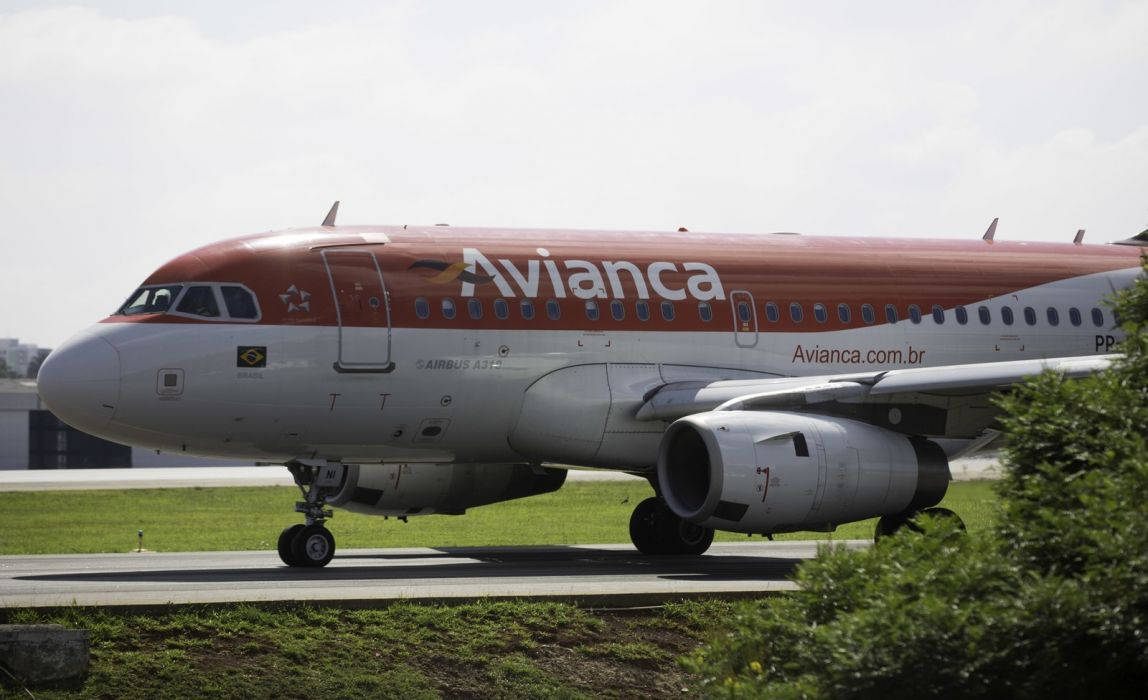 Plane 桌布 壁紙 — 一架 Avianca 空中巴士 A320 噴射客機在明亮的天空下，於跑道滑行，前景有綠草和灌木。
