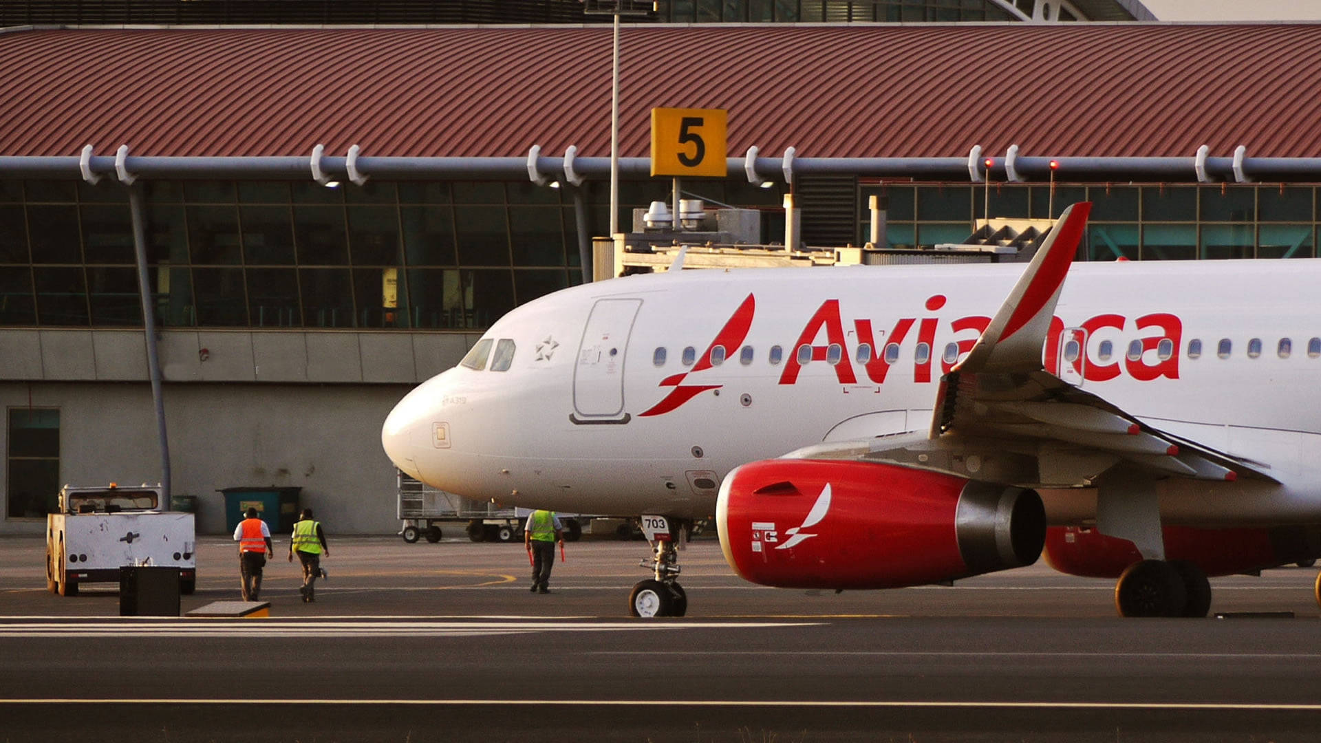 Airport 桌布 壁紙 — 一架 Avianca 飛機停在 5 號閘口，地勤人員在黃金時段於停機坪附近行走。