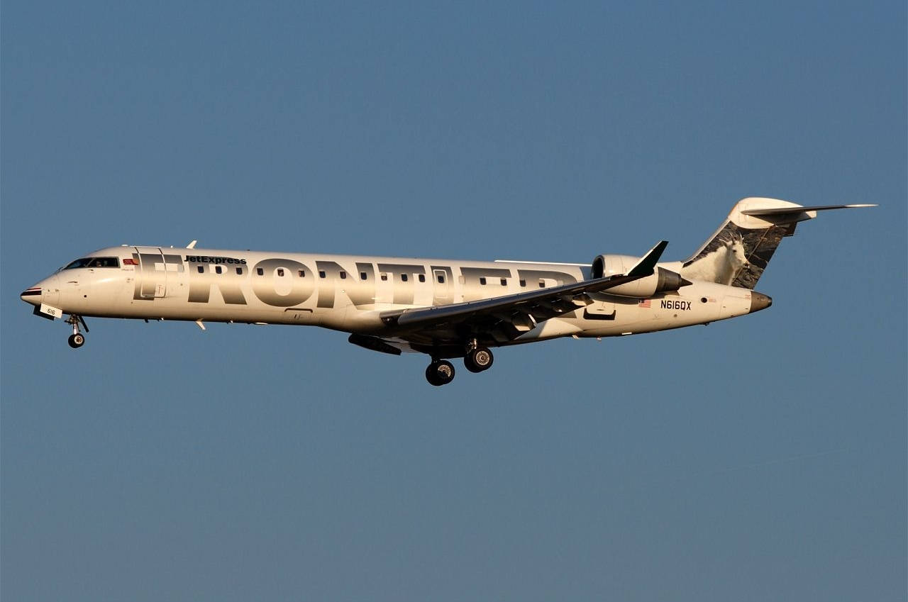 transportation 桌布 壁紙 — 一架 Frontier Airlines 區域噴射機在晴朗藍天下向左傾斜，起落架已放下。