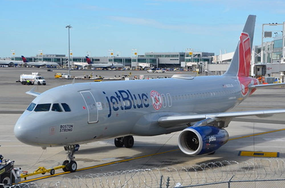 Plane 桌布 壁紙 — 一架 JetBlue 空中巴士 A320 停泊在機場閘口，背景是晴朗藍天、航廈和地勤人員。