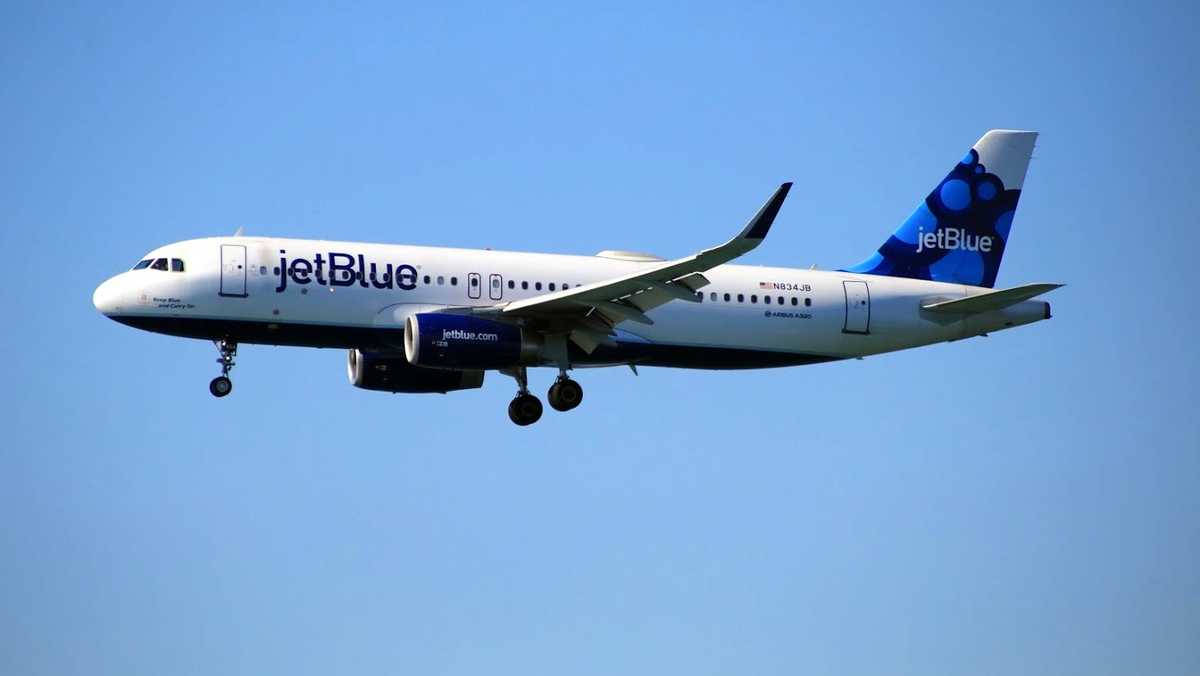 Plane 桌布 壁紙 — 一架 JetBlue 空中巴士 A320 飛機在晴朗藍天下飛行，起落架已放下。