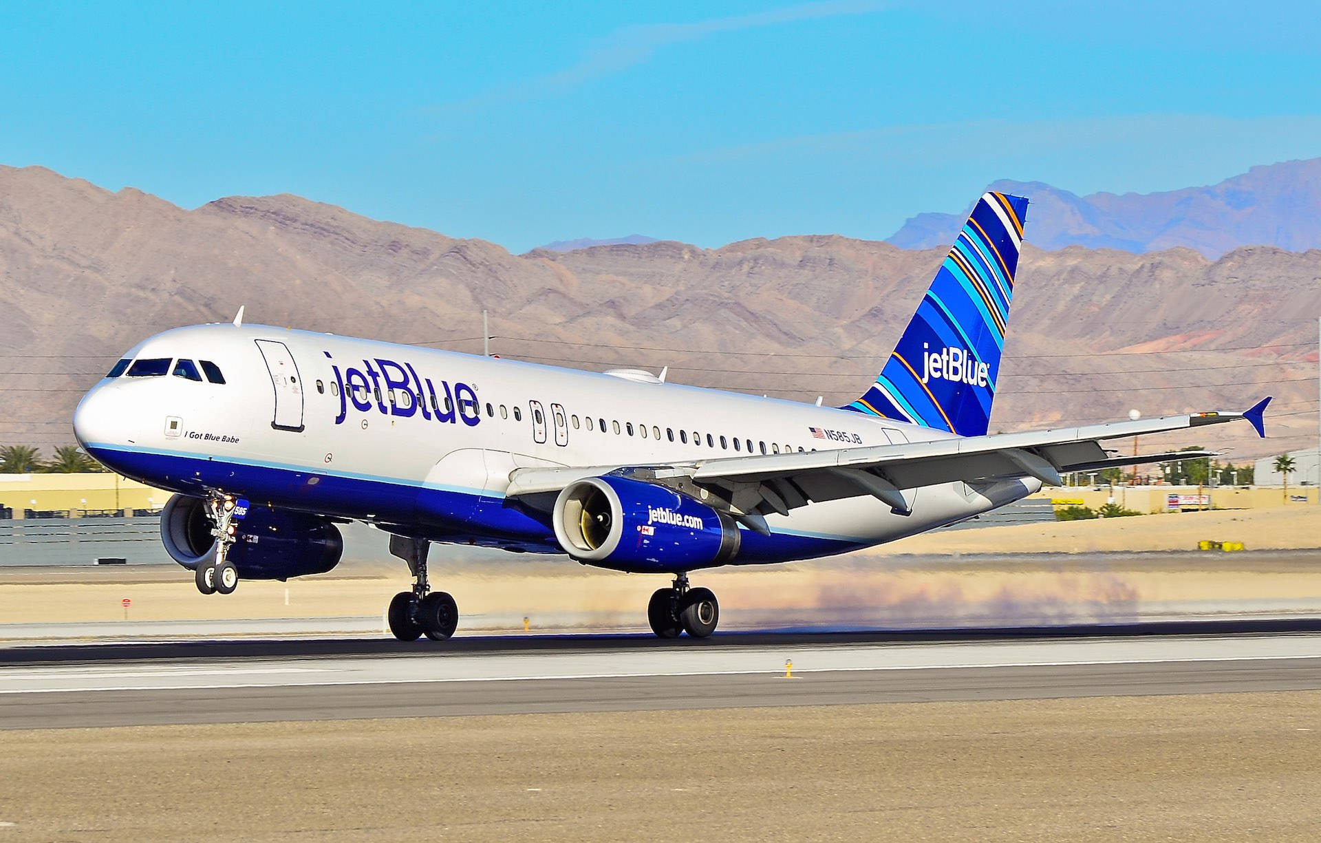 Plane 桌布 壁紙 — 一架 JetBlue 空中巴士 A320 在乾旱山脈和清澈藍天下於跑道上滑行。