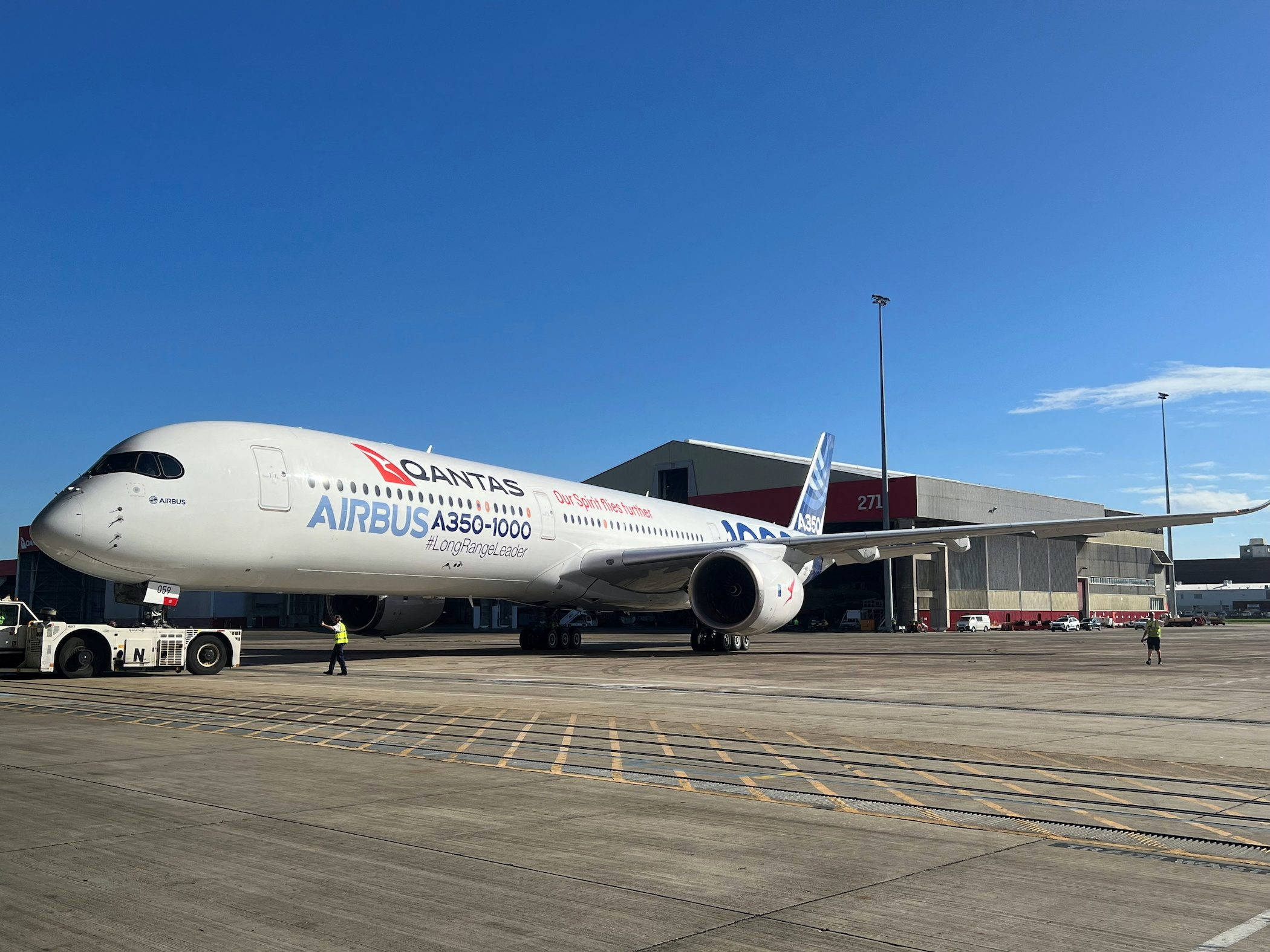 Airport 桌布 壁紙 — 一架 Qantas 空中巴士 A350-1000 飛機停放在機場停機坪上，天空晴朗蔚藍，附近有地勤人員。