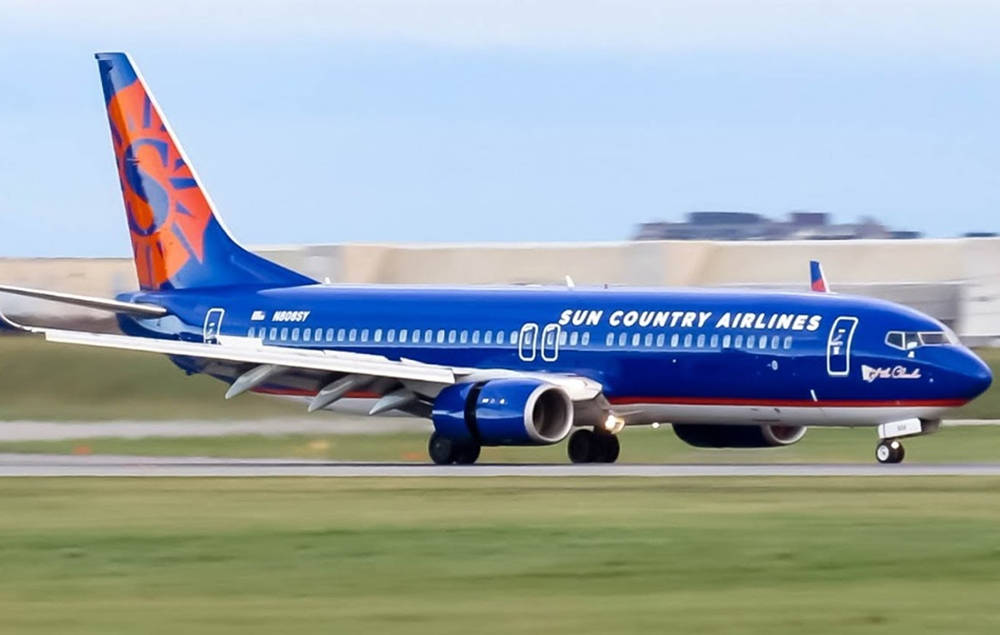 Airport 桌布 壁紙 — 一架 Sun Country Airlines 波音 737 在晴朗天空下滑行於跑道，背景模糊。