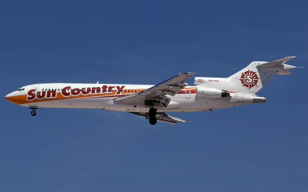 飛機 桌布 壁紙 — 一架 Sun Country Airlines 噴射機放下起落架，在清澈的藍天中翱翔。
