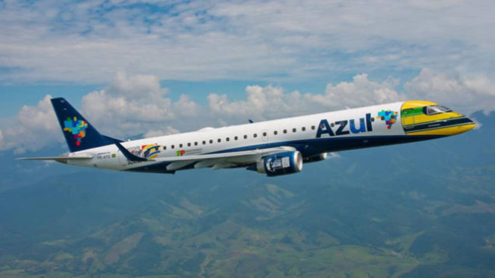 山脈 桌布 壁紙 — 一架Azul Airlines飛機在點綴著蓬鬆白雲的明亮藍天下，優雅地翱翔於起伏的綠色山脈之上。