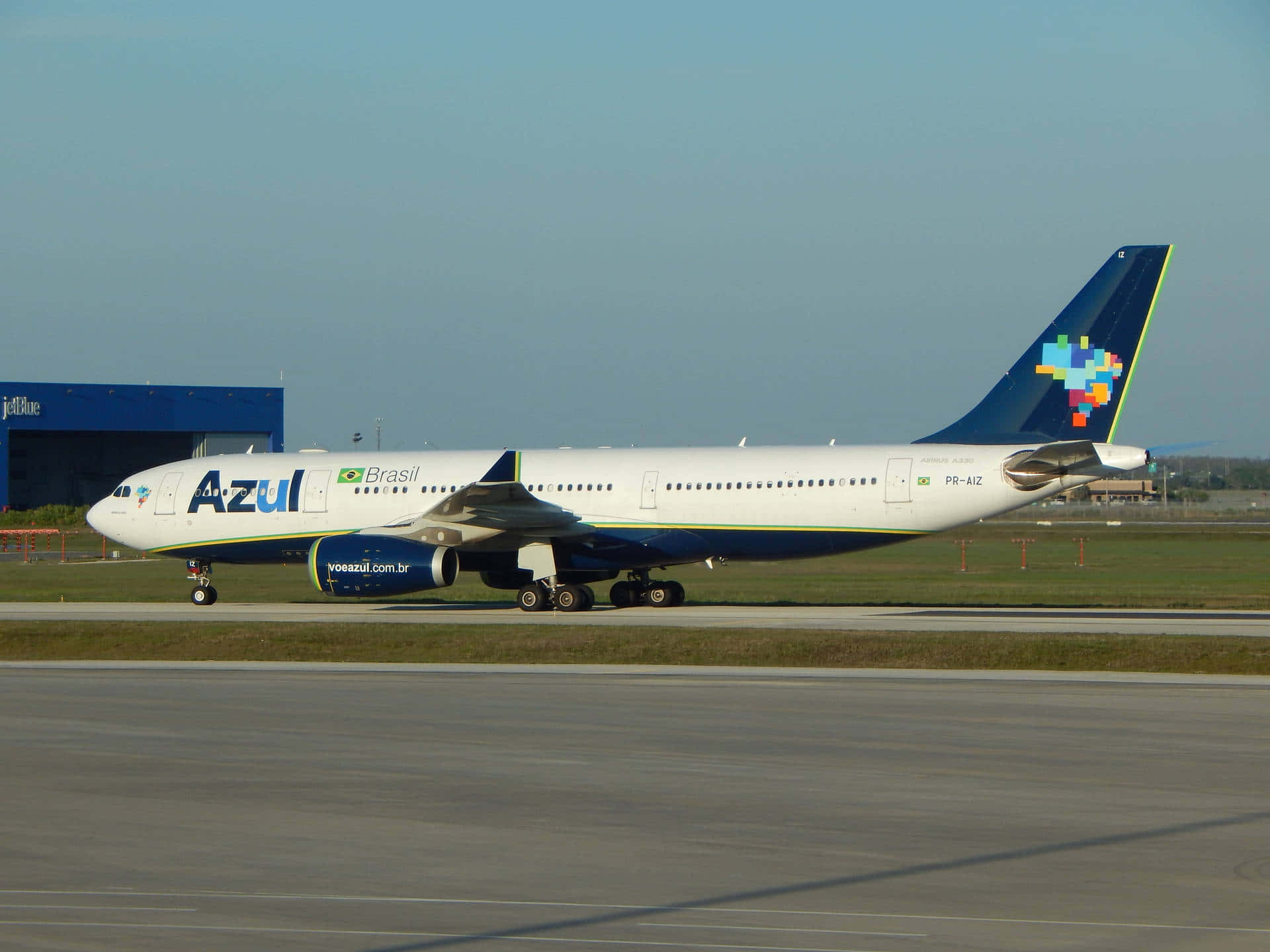Airport 桌布 壁紙 — 一架Azul Brasil的空中巴士A330在陽光普照的機場停機坪上滑行，背景是晴朗的藍天和遠處的機庫。