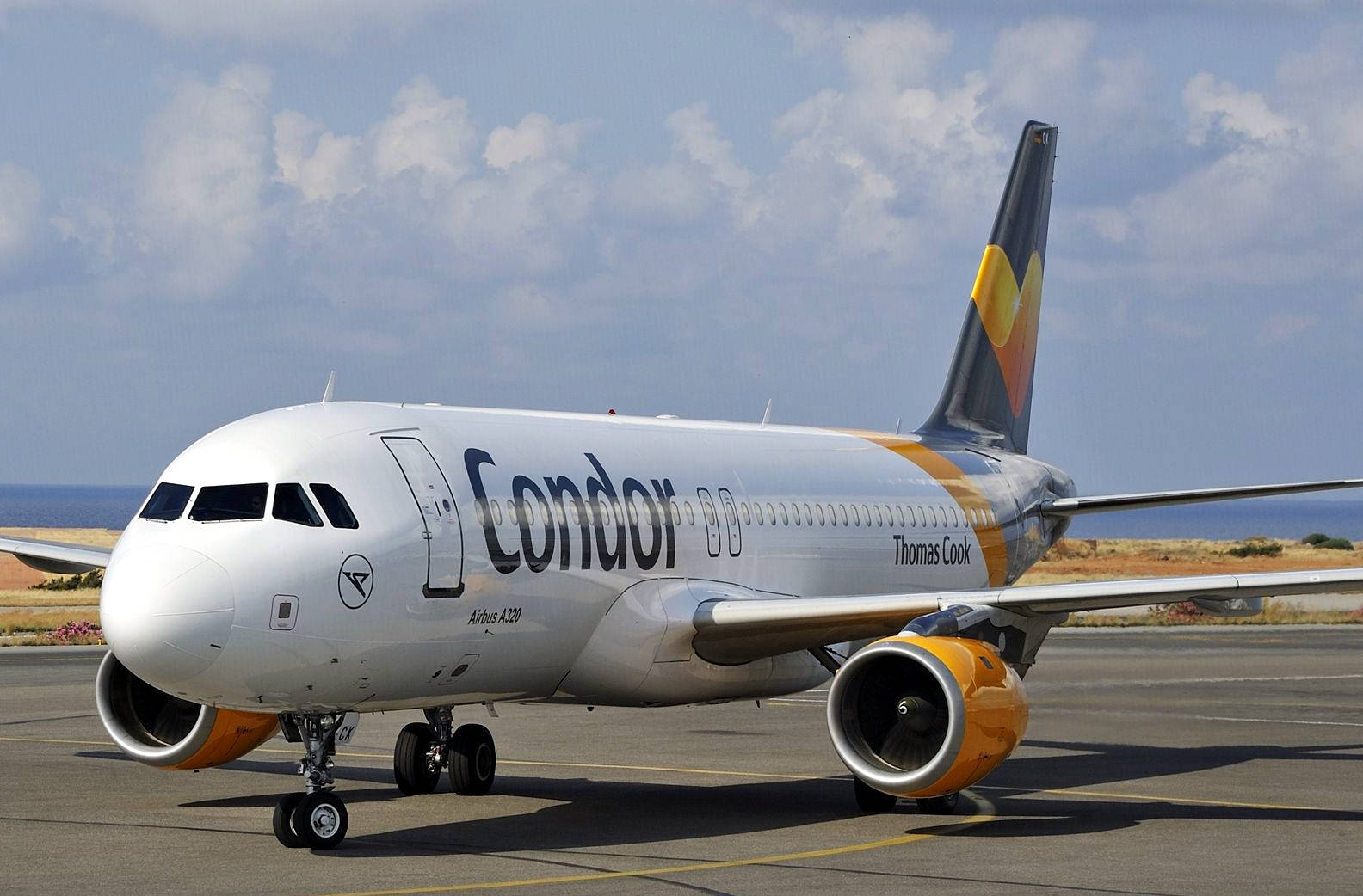 Airport 桌布 壁紙 — 一架Condor Thomas Cook空中巴士A330停泊在機場停機坪上，背景有海洋和陰天。