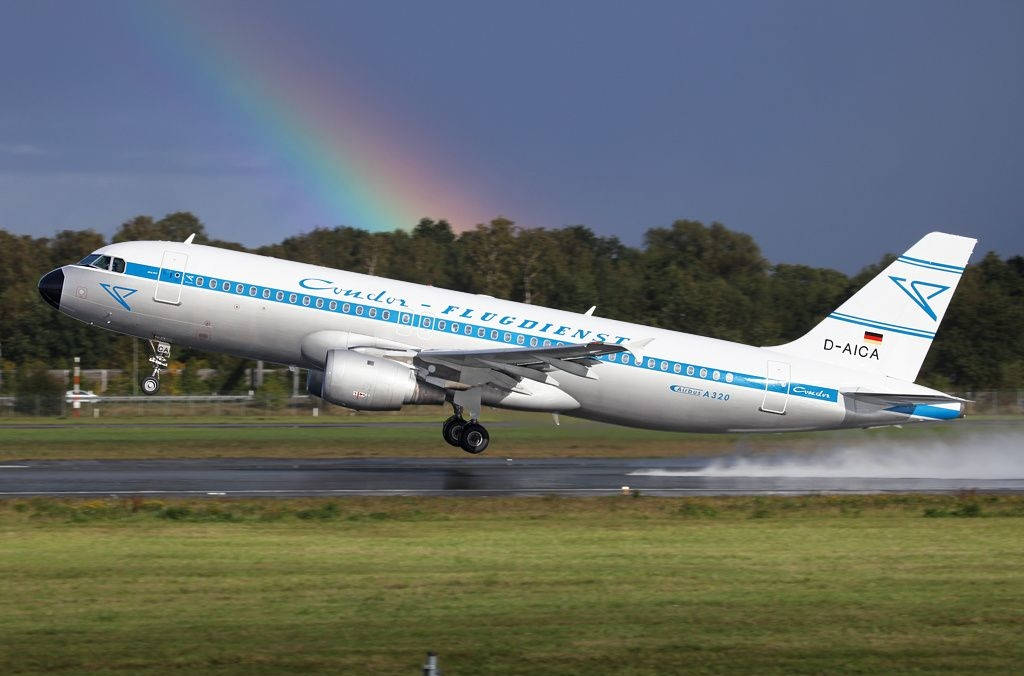 飛機 桌布 壁紙 — 一架Condor空中巴士A320從跑道起飛，背後一道鮮豔的彩虹橫跨清澈的藍天。